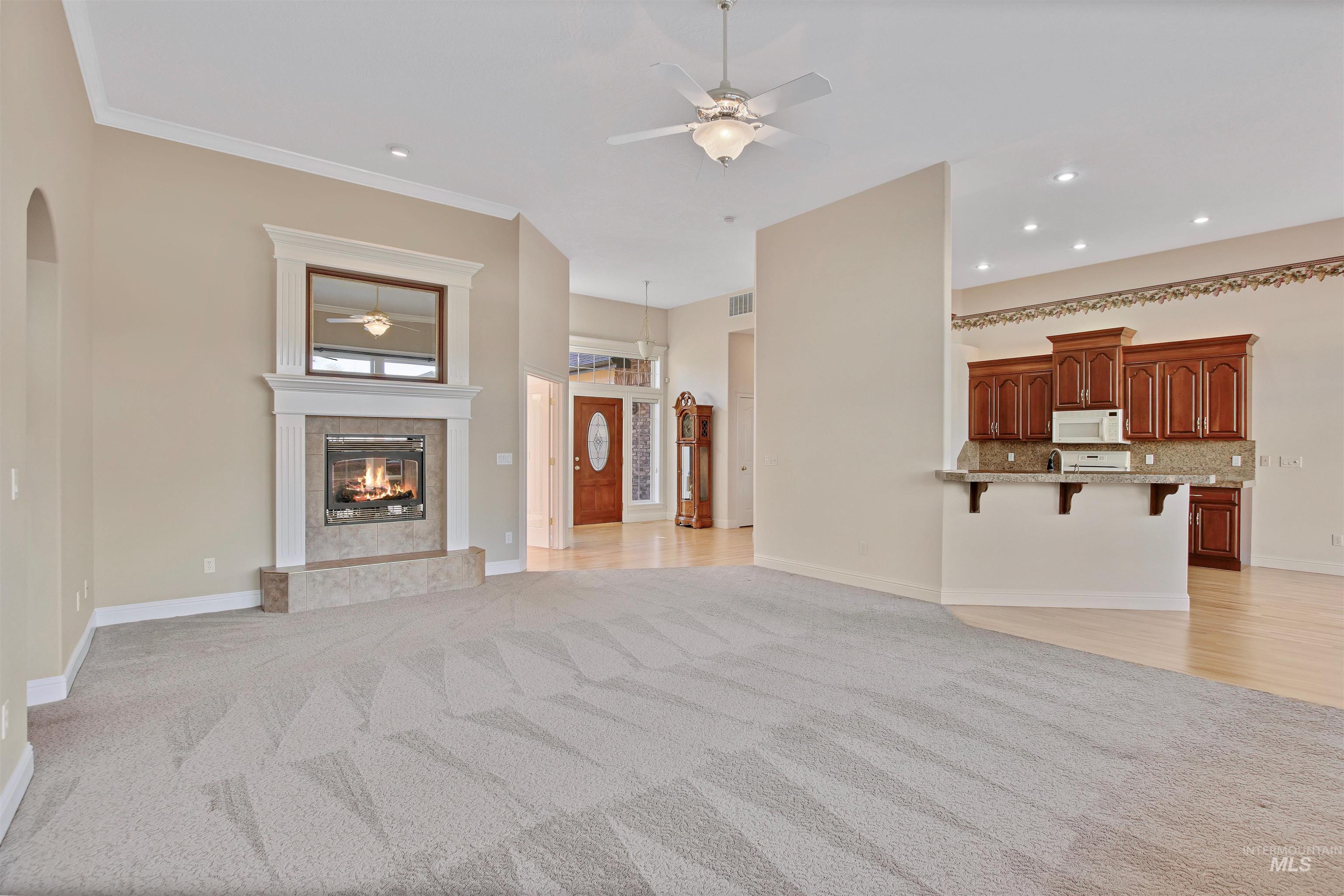 Unfurnished living room featuring a ceiling fan, light carpet, arched walkways, recessed lighting, and a premium fireplace
