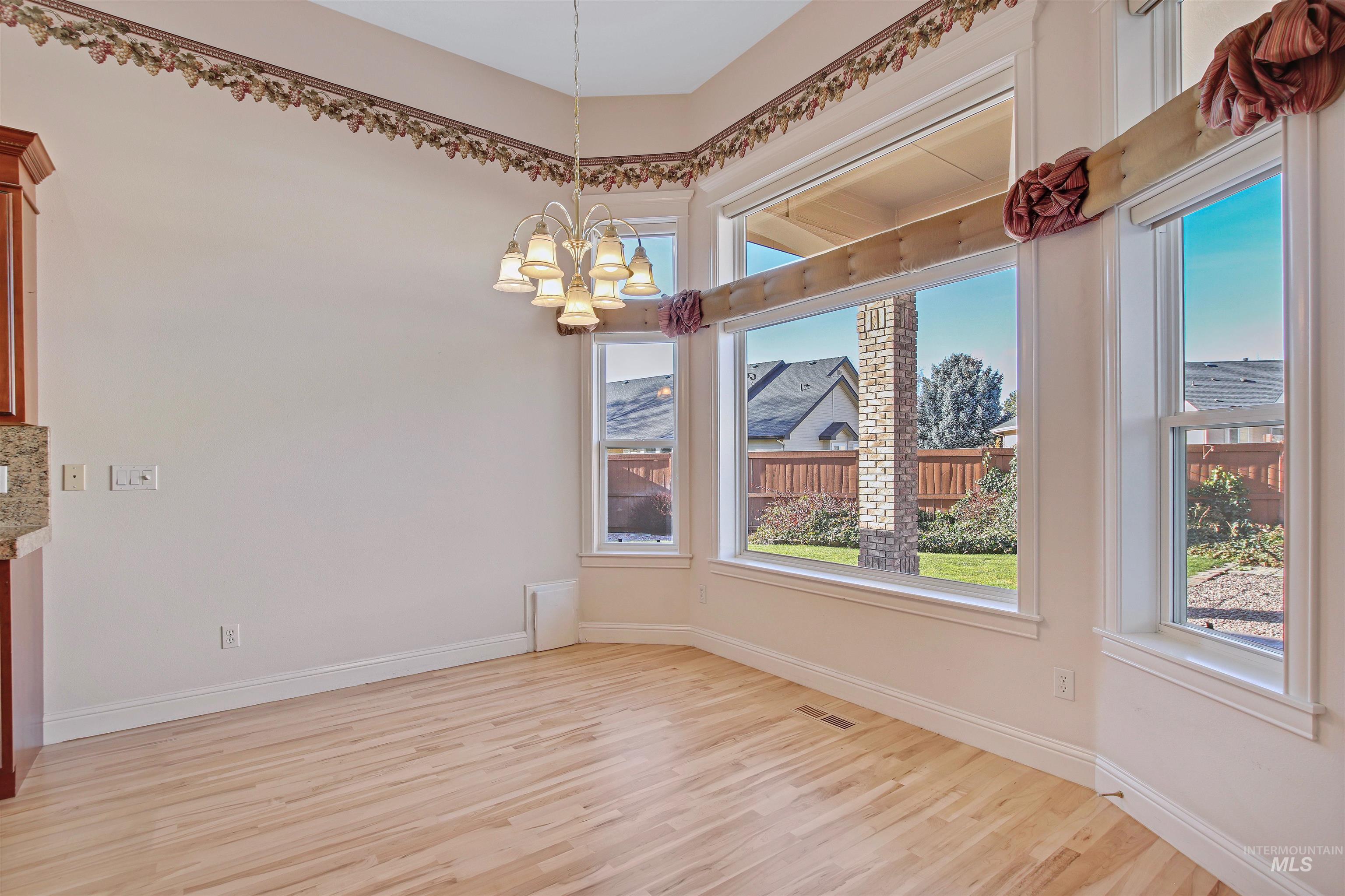 Unfurnished dining area featuring light wood finished floors and a chandelier