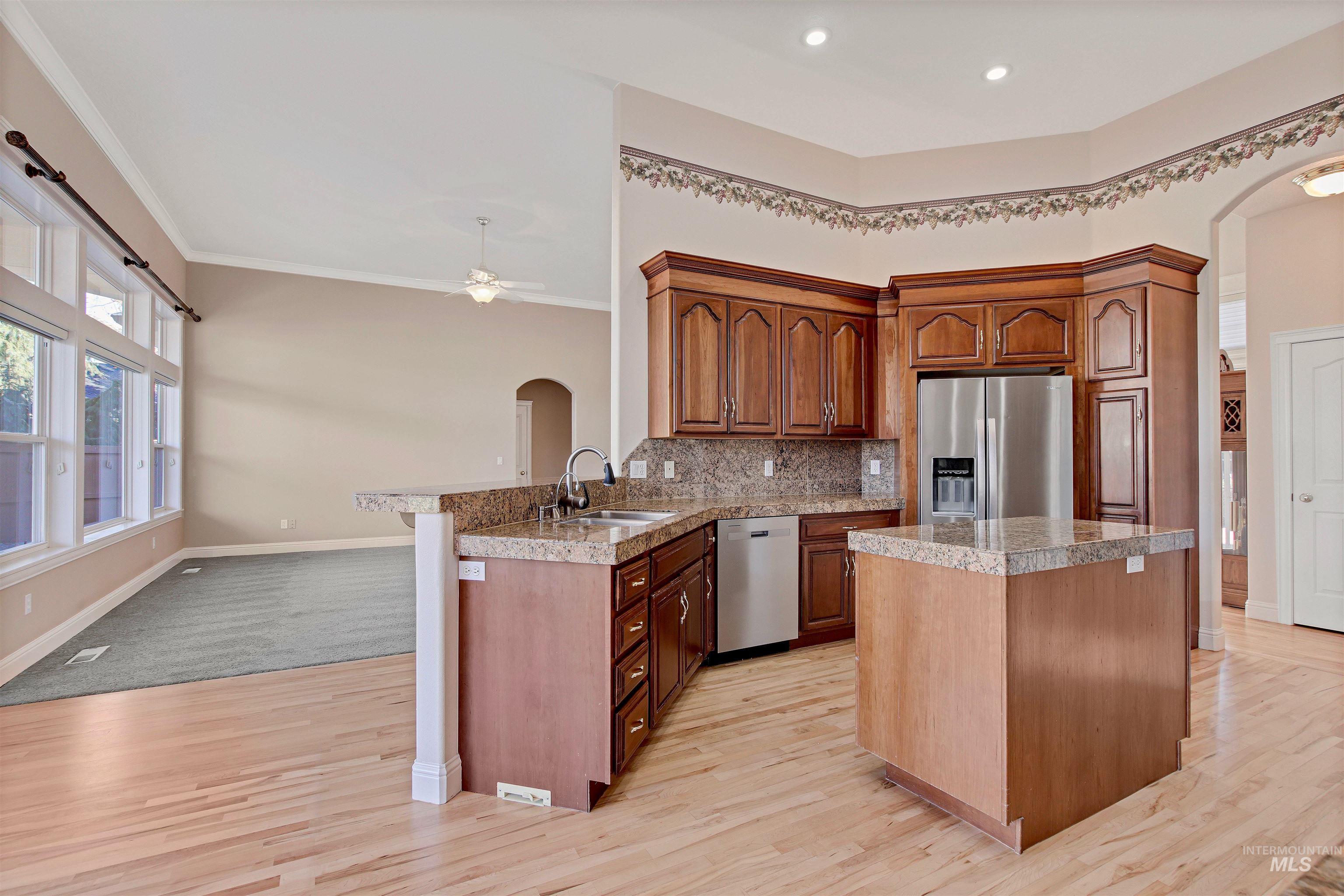 Kitchen featuring arched walkways, a breakfast bar area, tile countertops, a center island, and crown molding