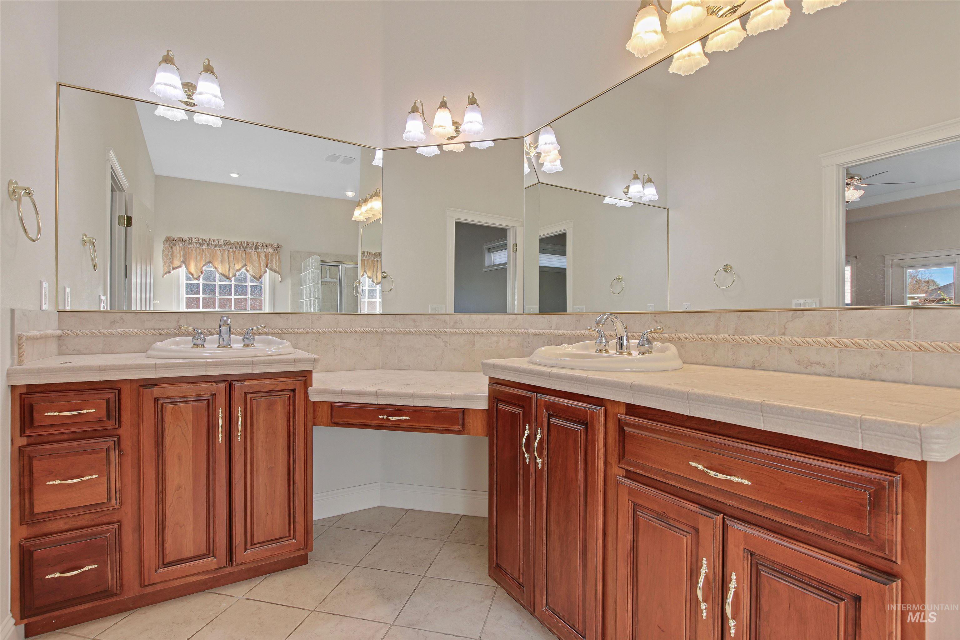 Bathroom featuring double vanity, light tile patterned floors, and ceiling fan