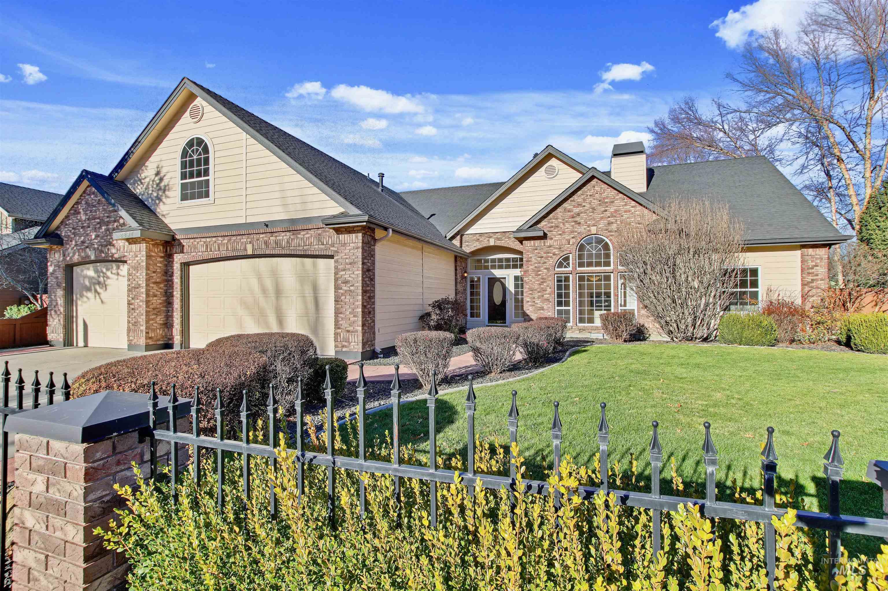 View of front facade featuring a chimney, brick siding, a garage, and roof with shingles