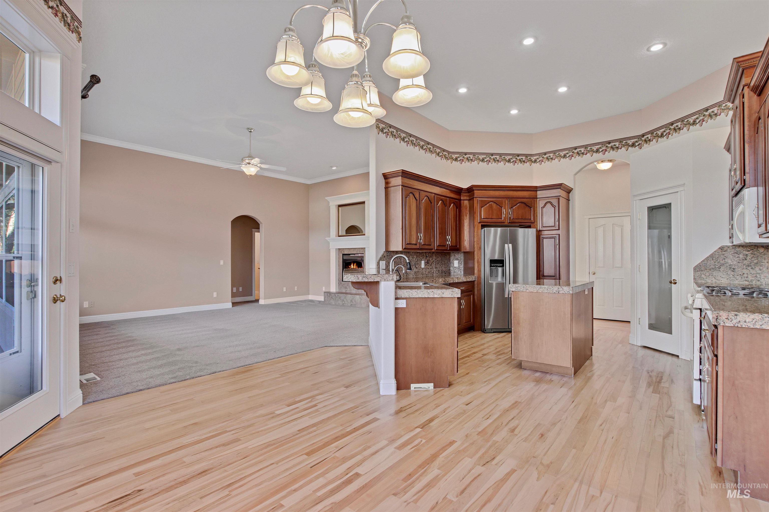 Kitchen featuring open floor plan, arched walkways, a center island, hanging light fixtures, and stainless steel fridge