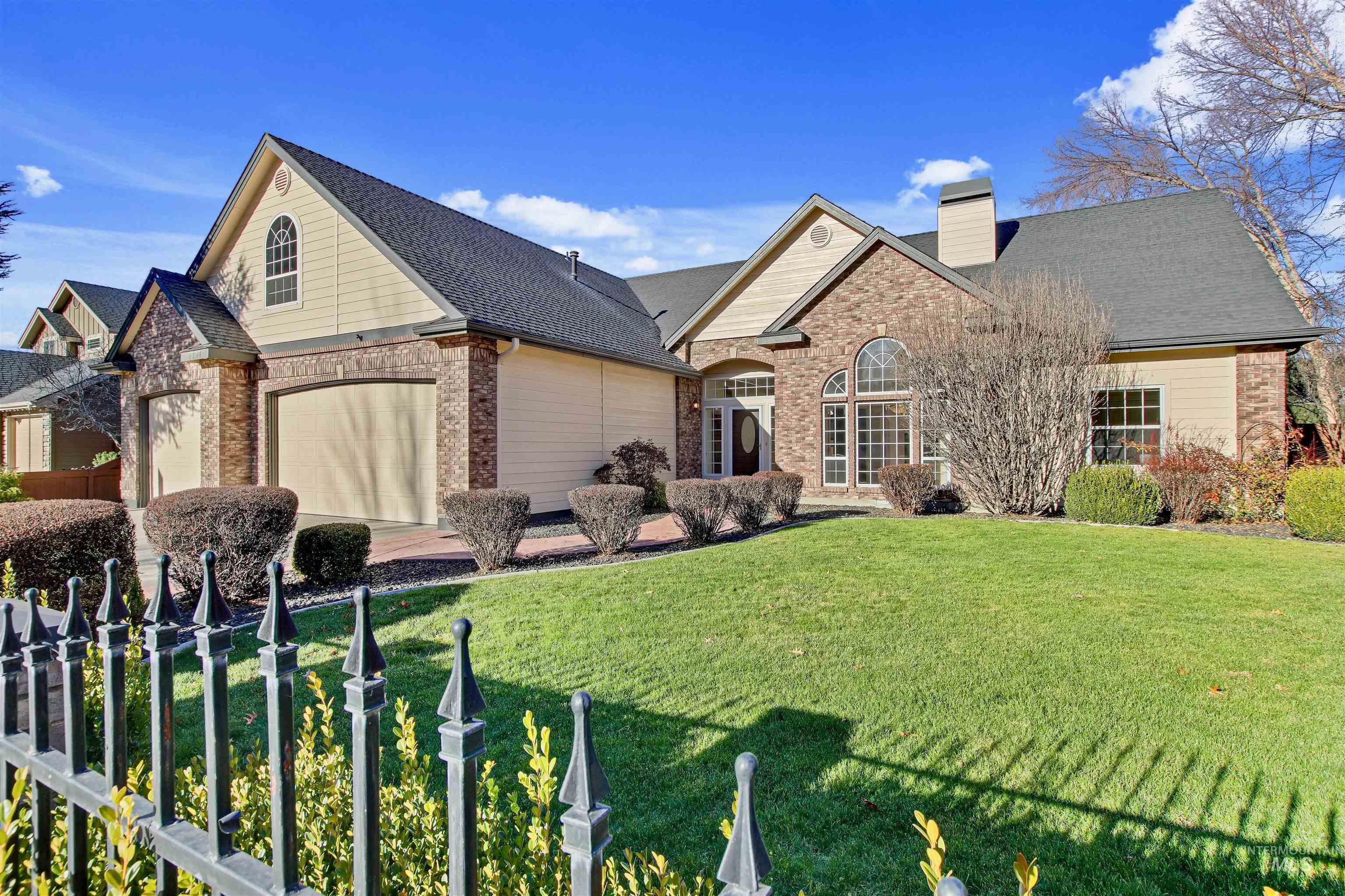 View of front of house featuring a chimney, a garage, brick siding, and a shingled roof
