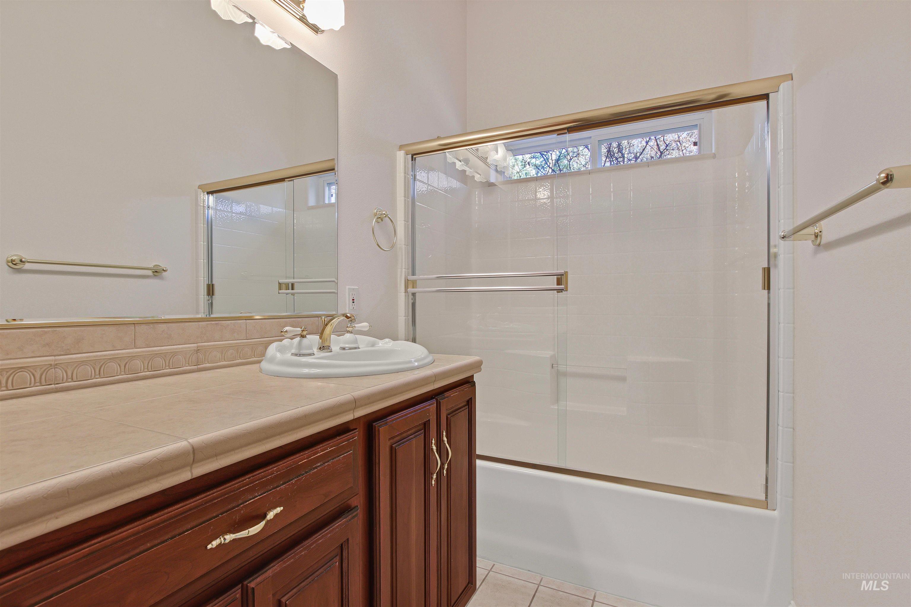 Bathroom with vanity, combined bath / shower with glass door, and light tile patterned floors