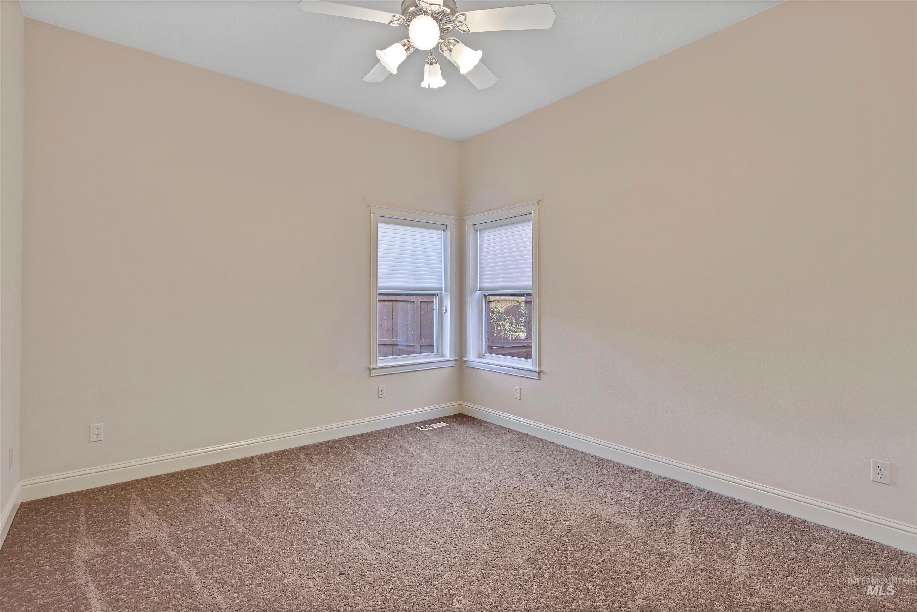 Carpeted empty room featuring baseboards and a ceiling fan