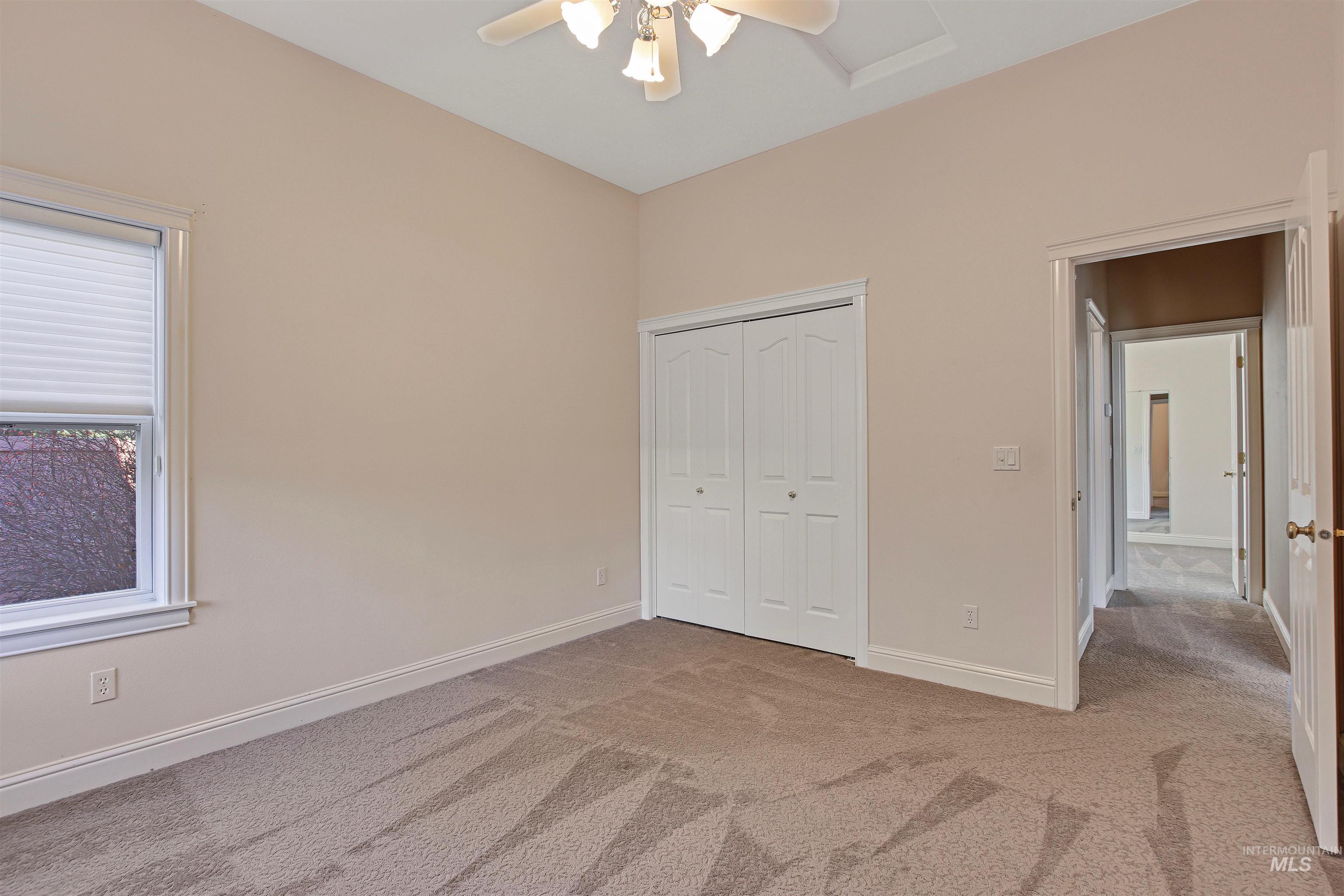 Unfurnished bedroom featuring light carpet, a closet, and a ceiling fan