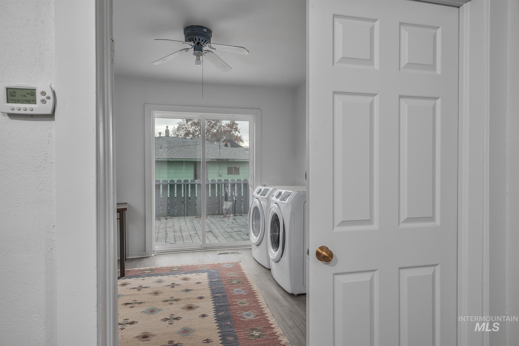Laundry room with washing machine and clothes dryer, light wood-style flooring, and ceiling fan