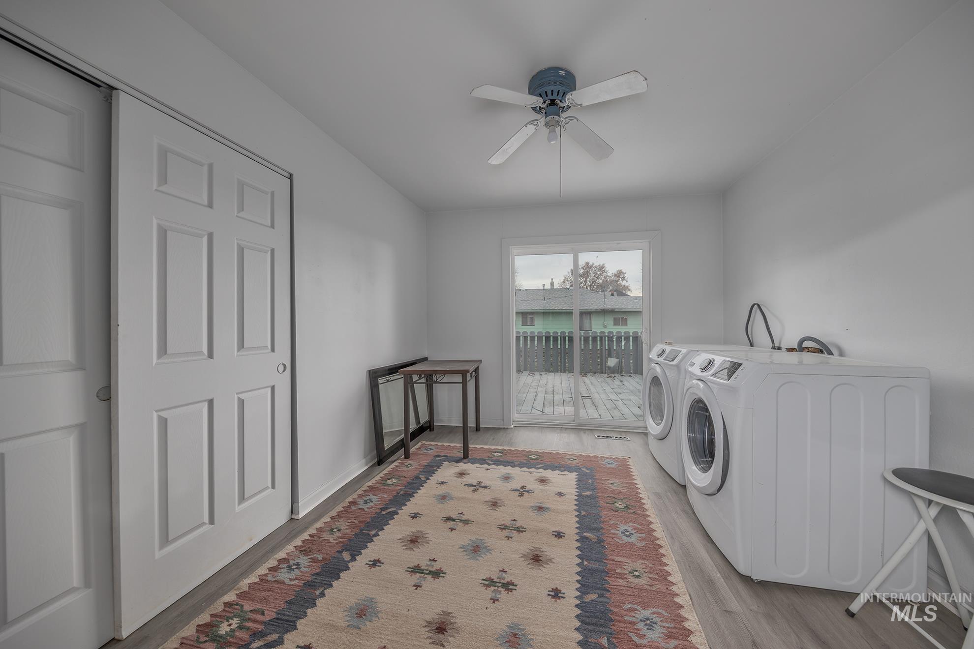 Laundry room featuring washer and clothes dryer, ceiling fan, and light wood-type flooring