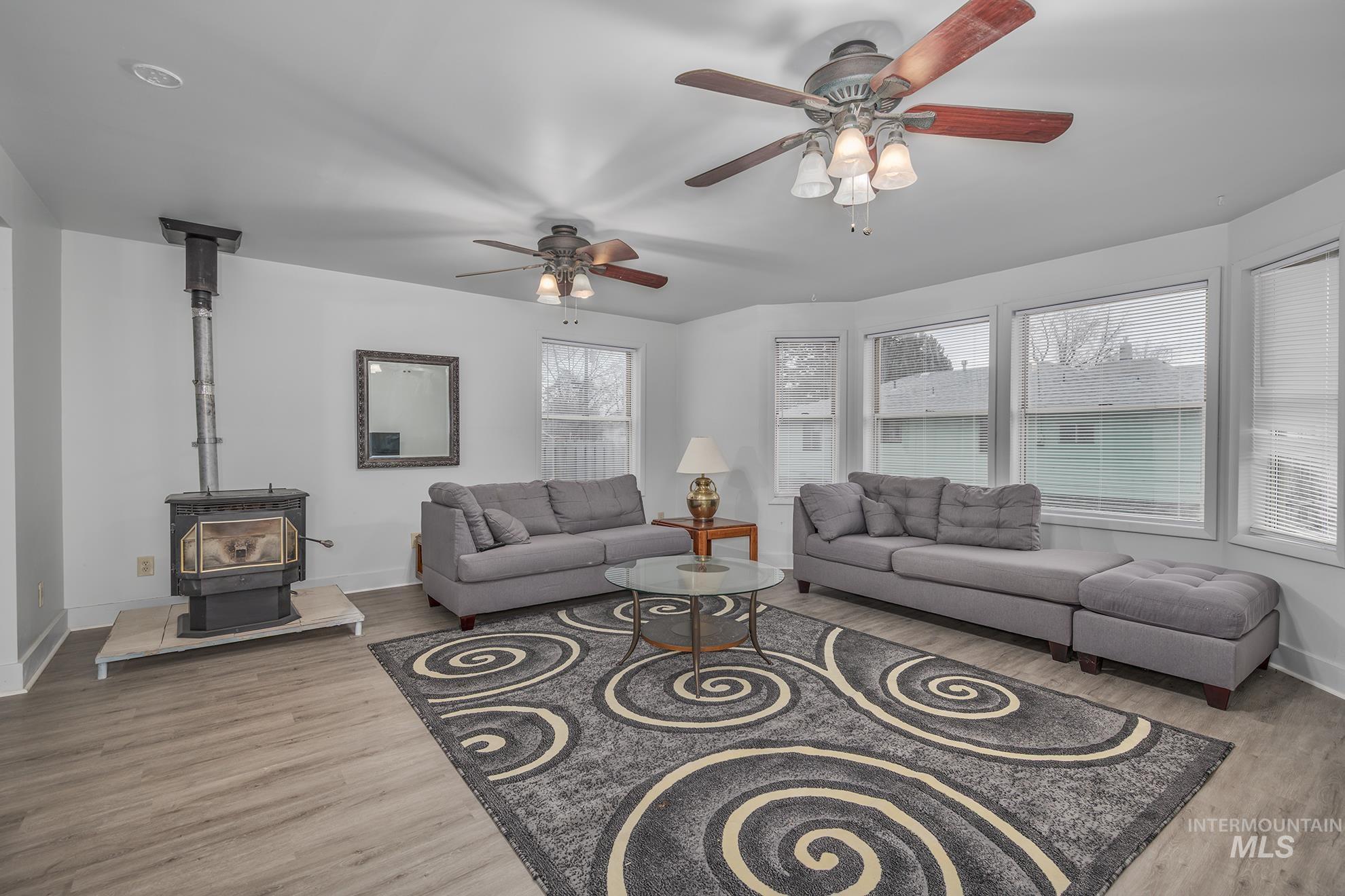 Living area with a wood stove, light wood-style floors, and ceiling fan