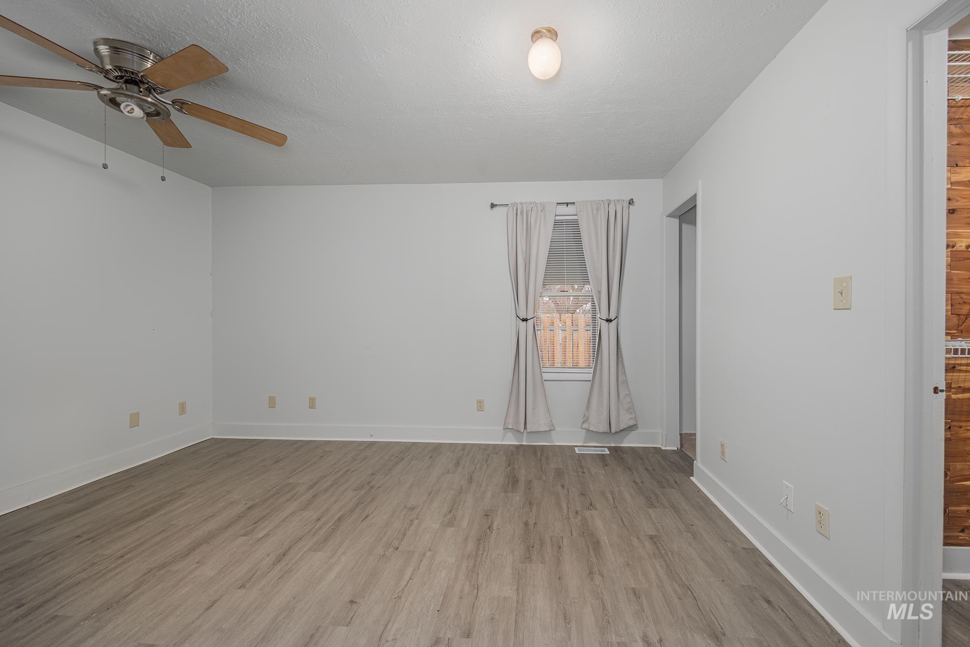 Spare room featuring light wood-type flooring, a ceiling fan, and a textured ceiling