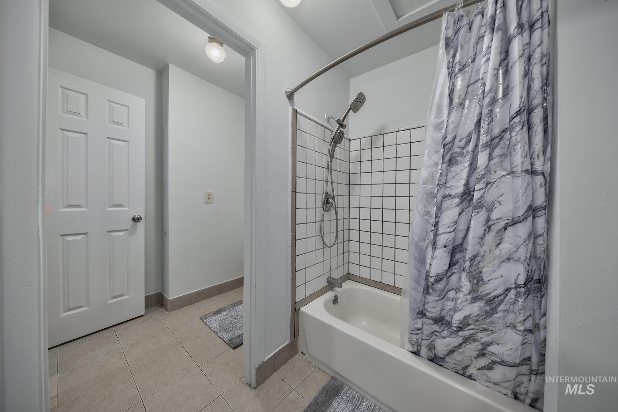 Full bath with shower / bath combo and light tile patterned floors