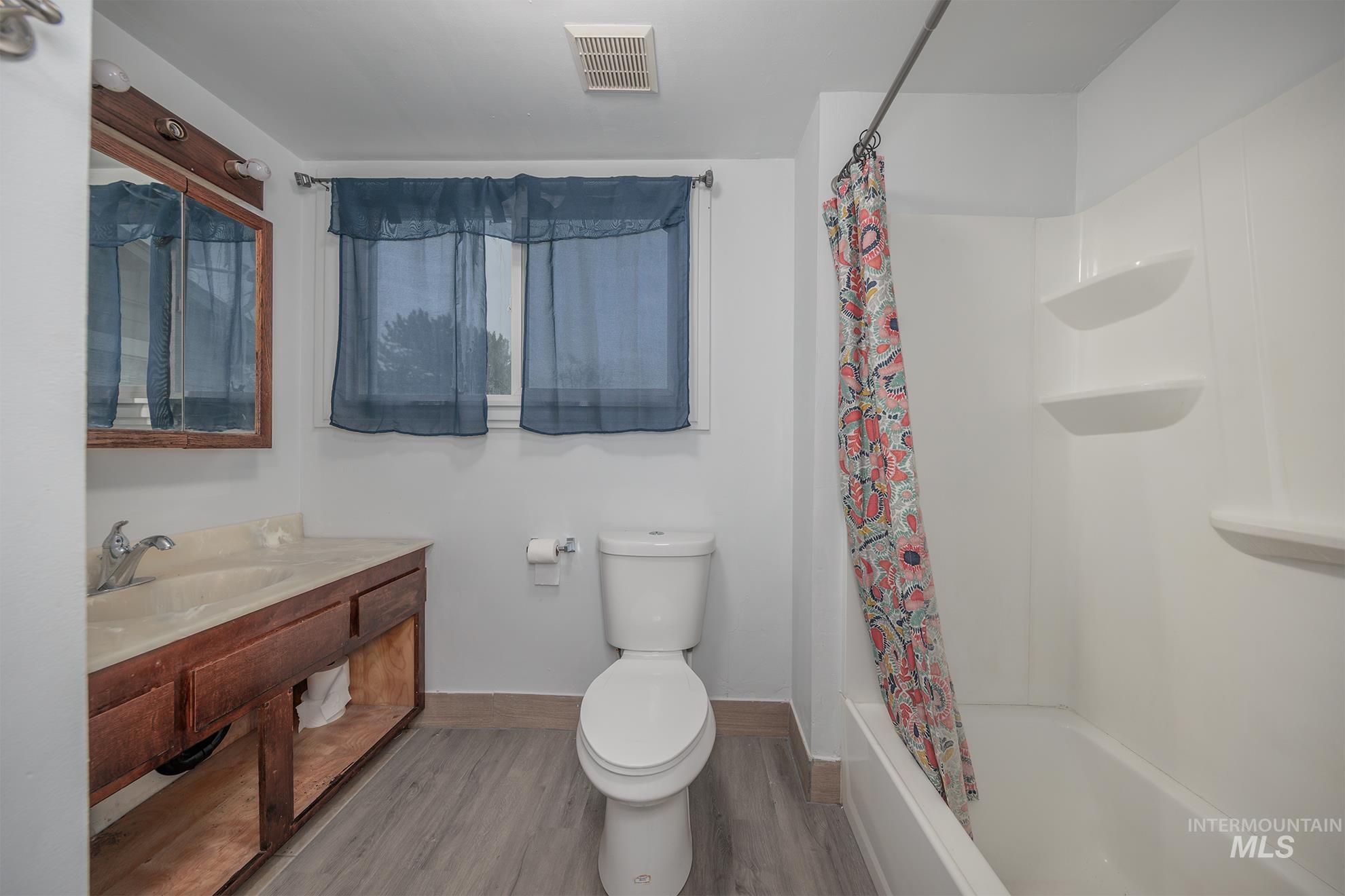 Bathroom with vanity, wood finished floors, and shower / bath combo with shower curtain