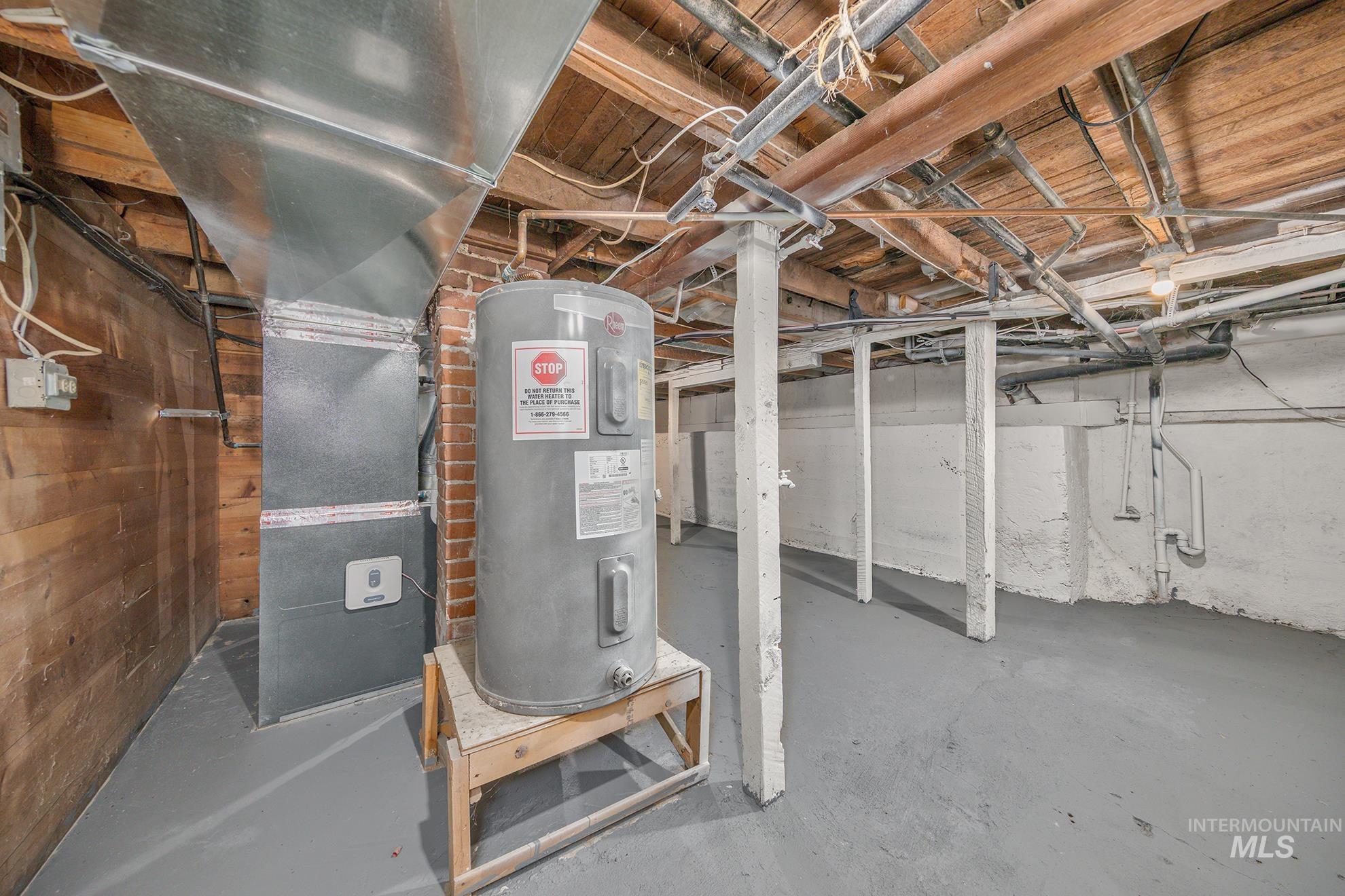 Unfinished below grade area featuring water heater and heating unit