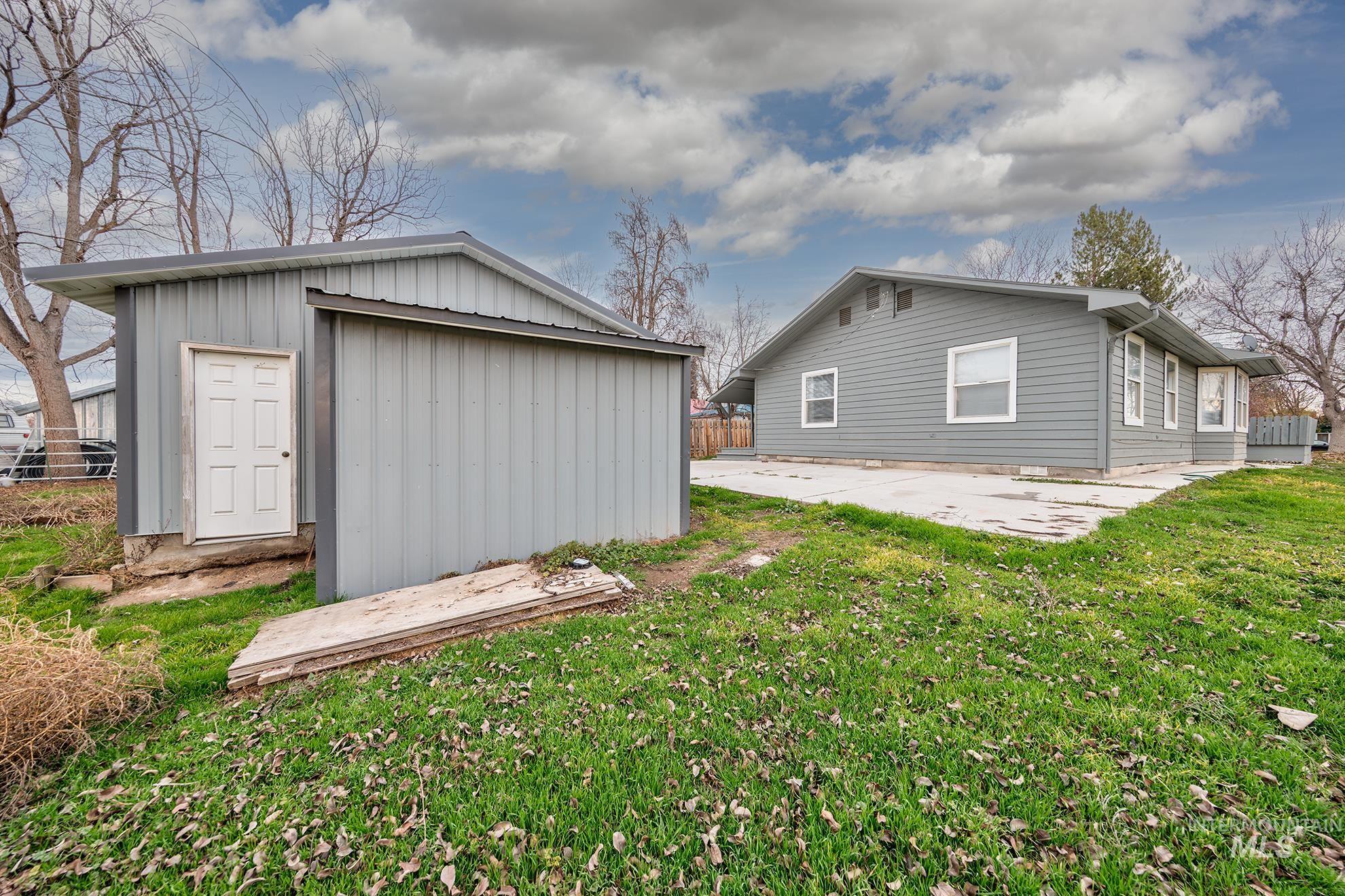 Rear view of property with a patio area, board and batten siding, and a storage unit