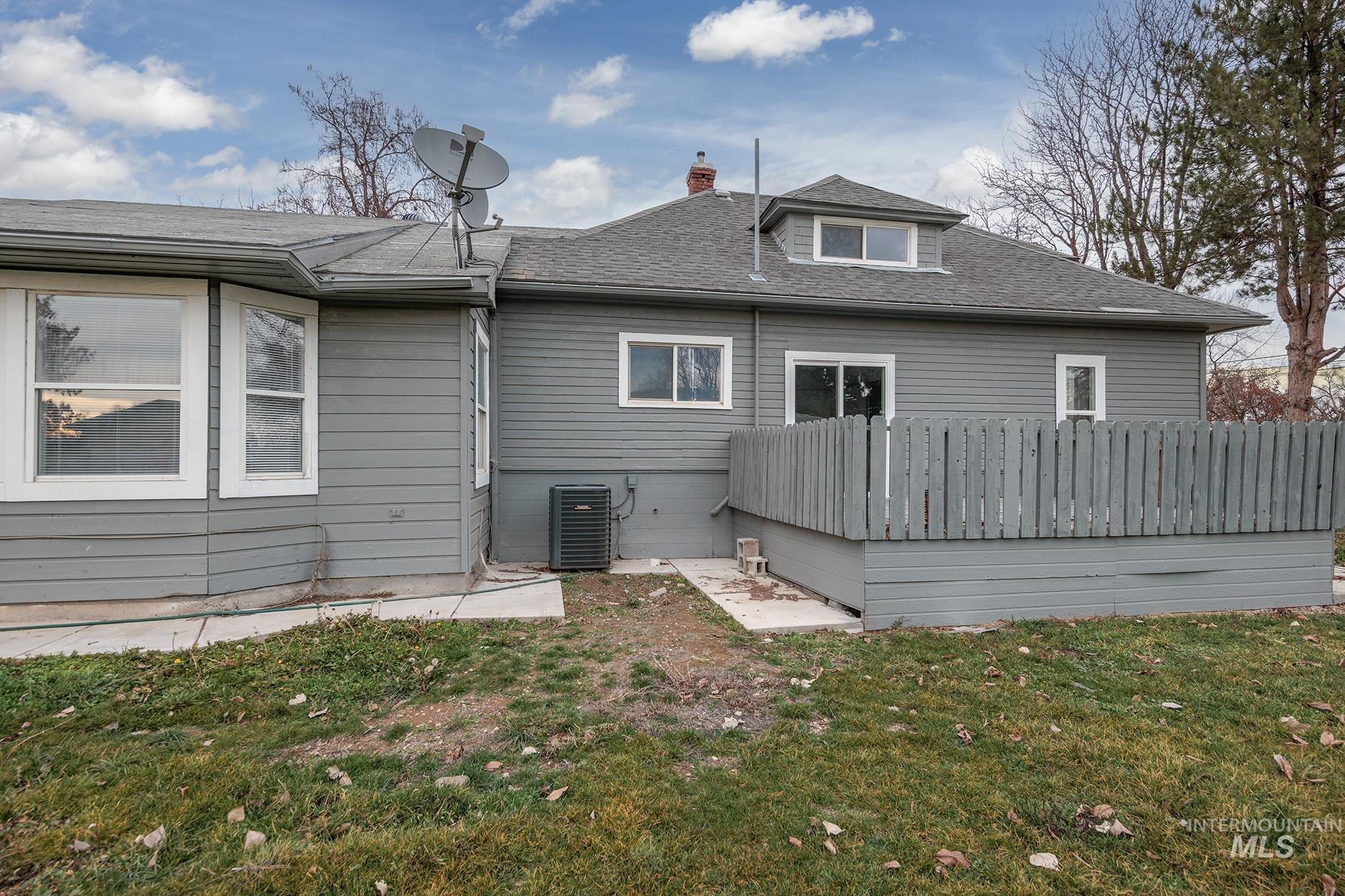 Back of house featuring roof with shingles, a chimney, and a wooden deck