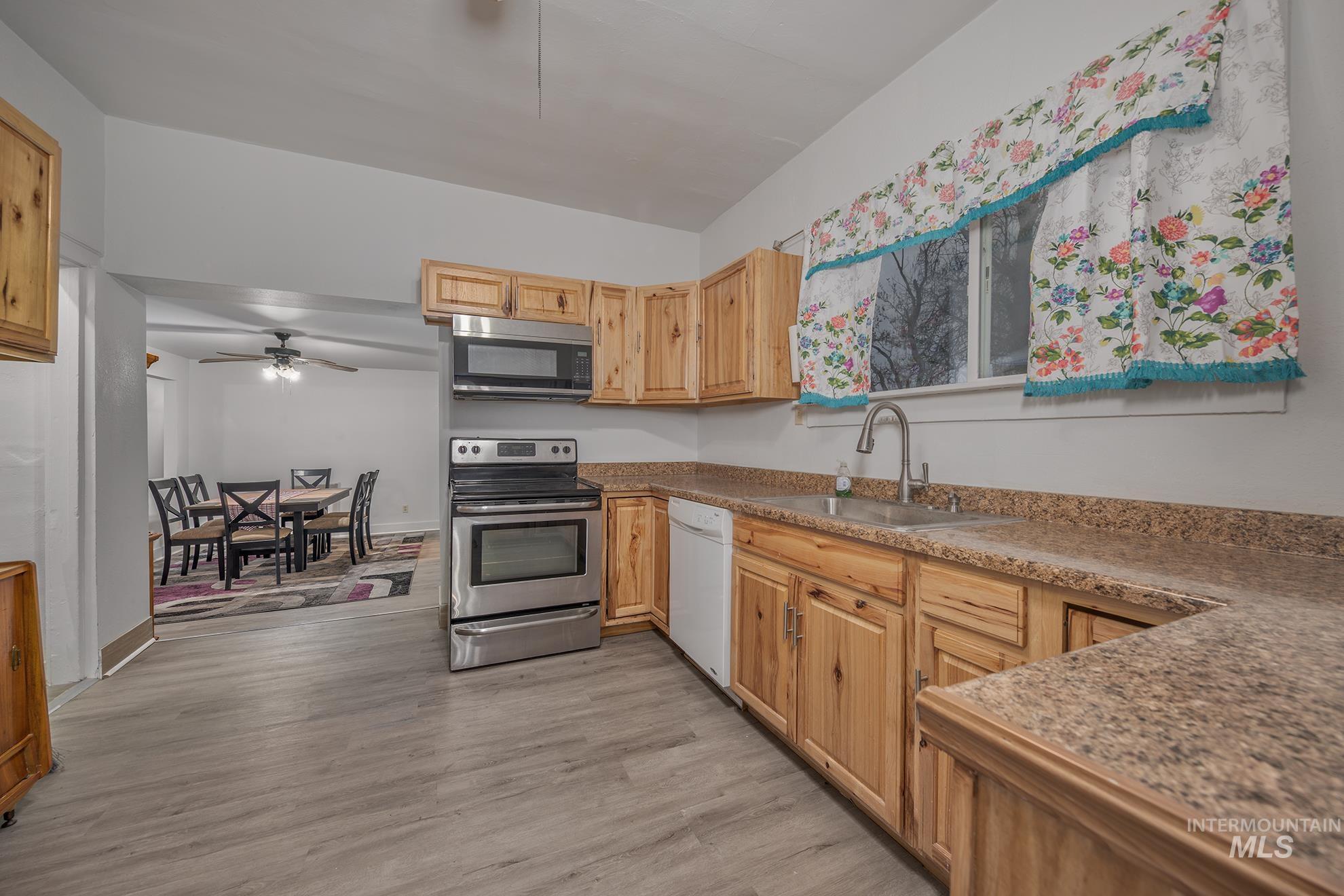 Kitchen featuring ceiling fan, stainless steel appliances, light brown cabinetry, and light wood-style floors