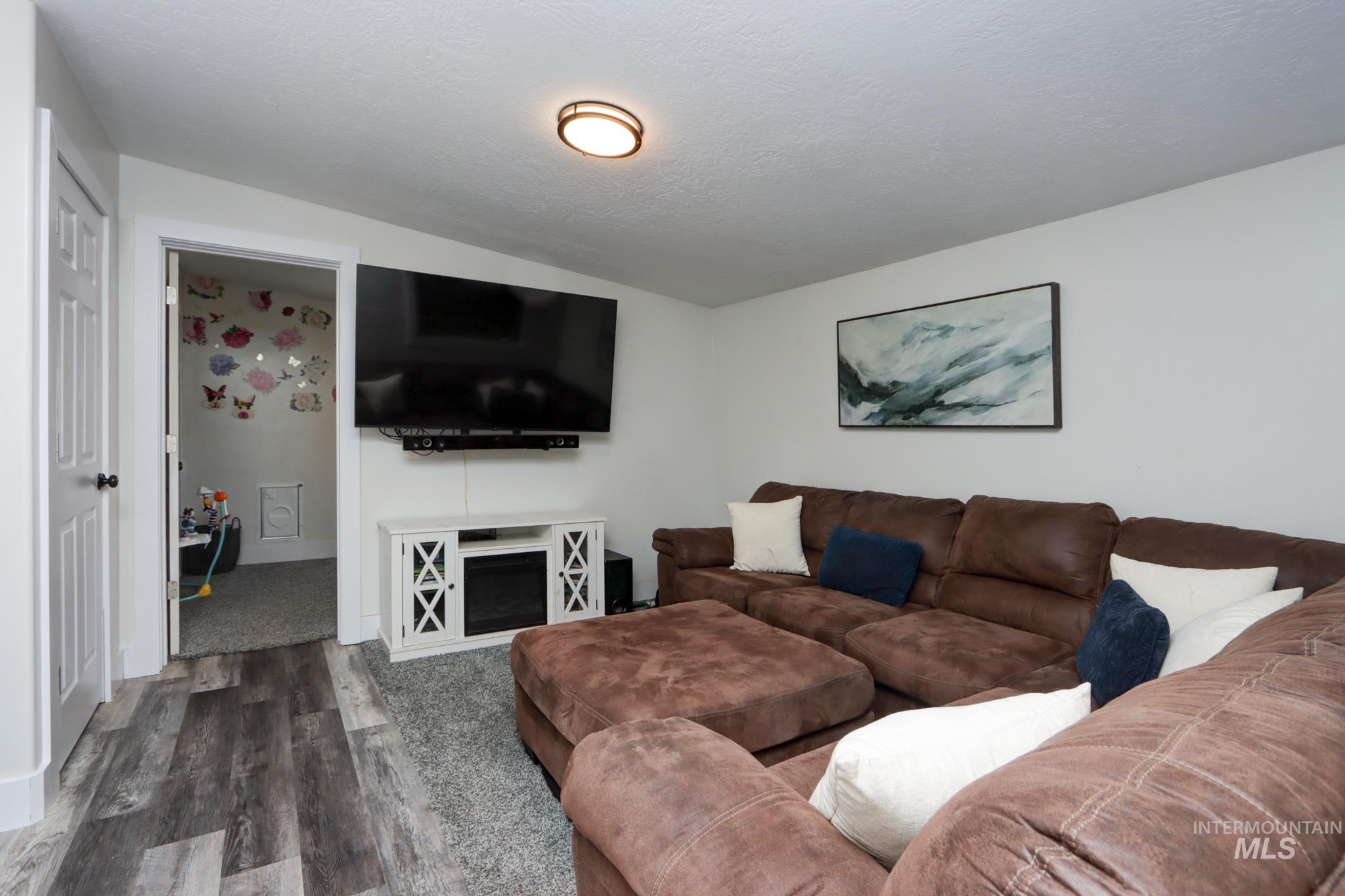 Living area with dark wood-type flooring, a textured ceiling, and lofted ceiling