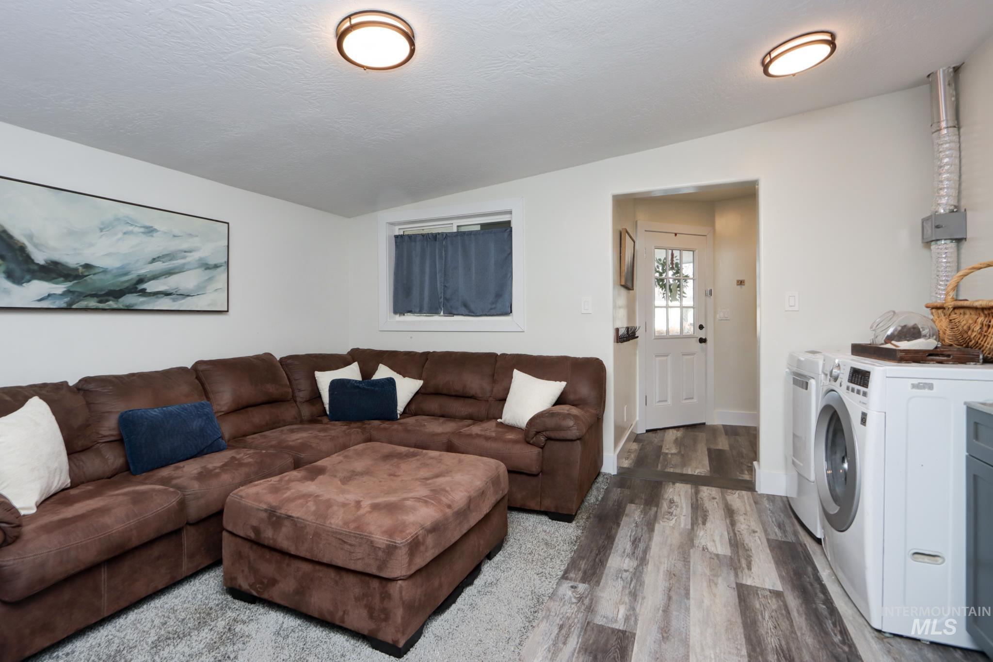 Living room featuring washer and dryer, lofted ceiling, and wood finished floors