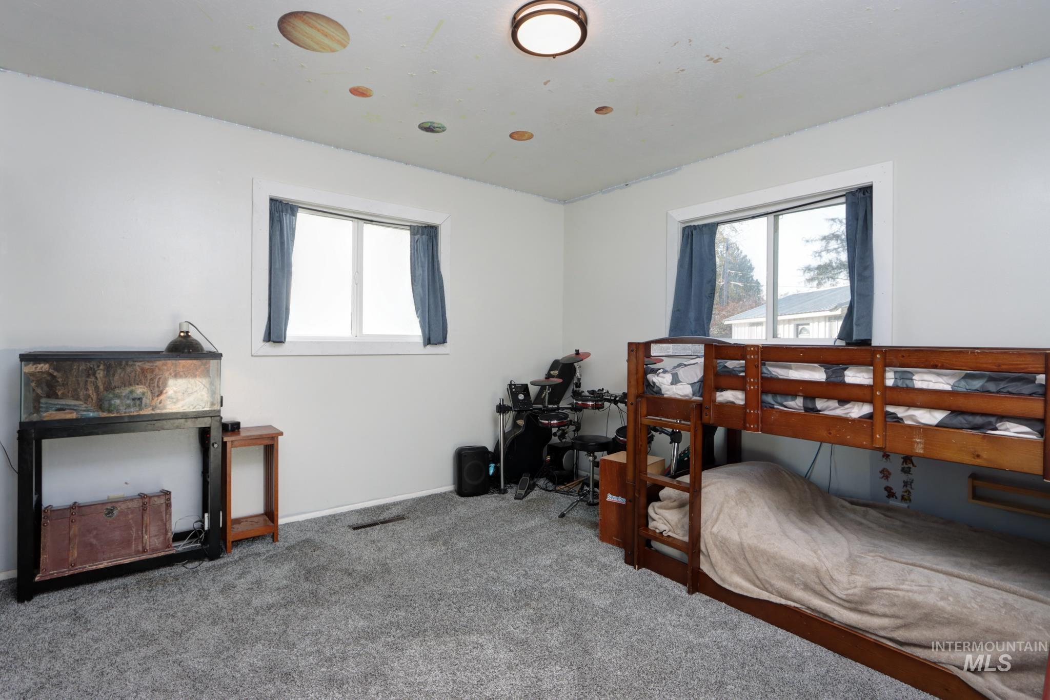 Carpeted bedroom featuring multiple windows