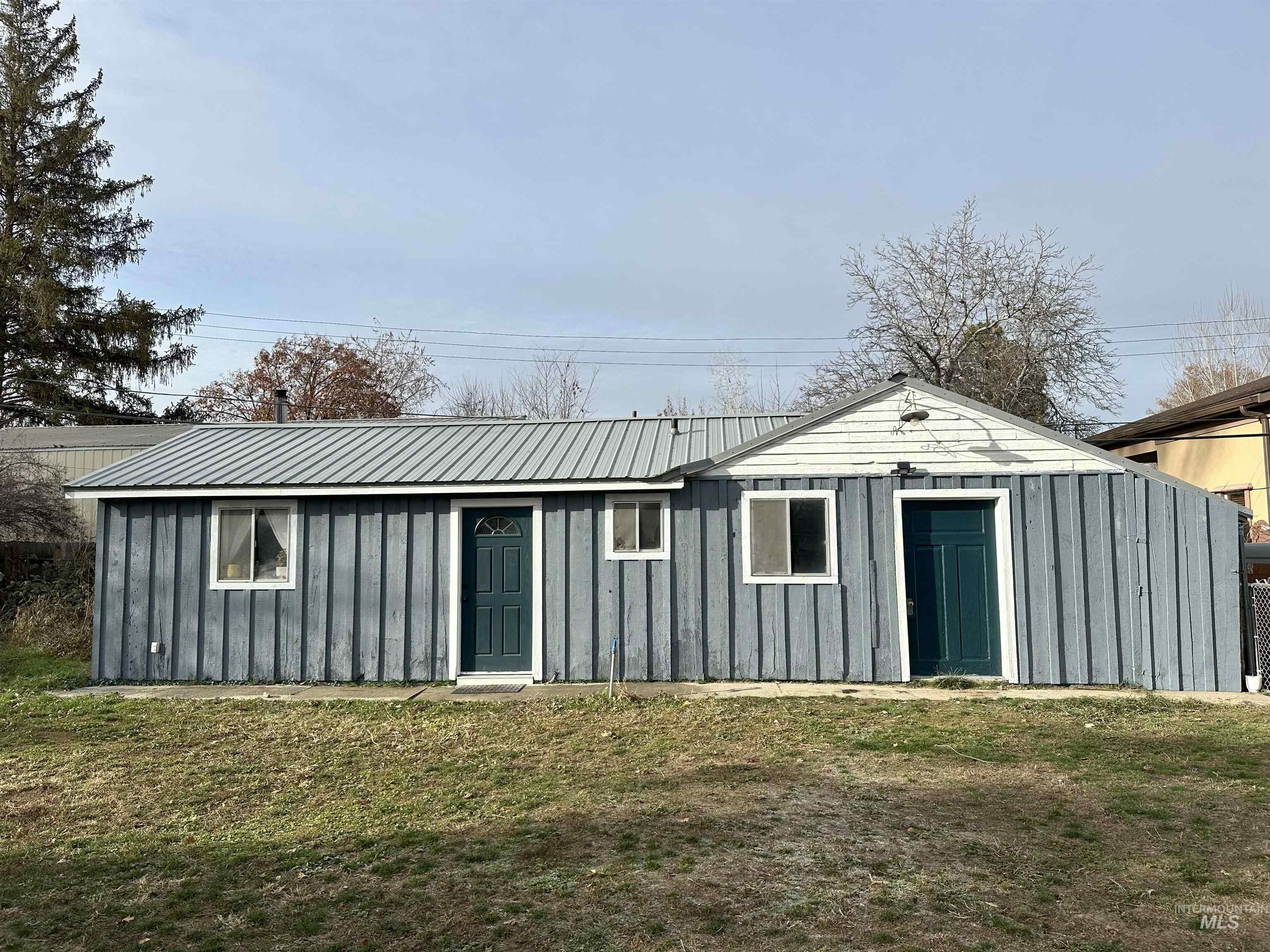 Rear view of house featuring board and batten siding, a yard, and a metal roof