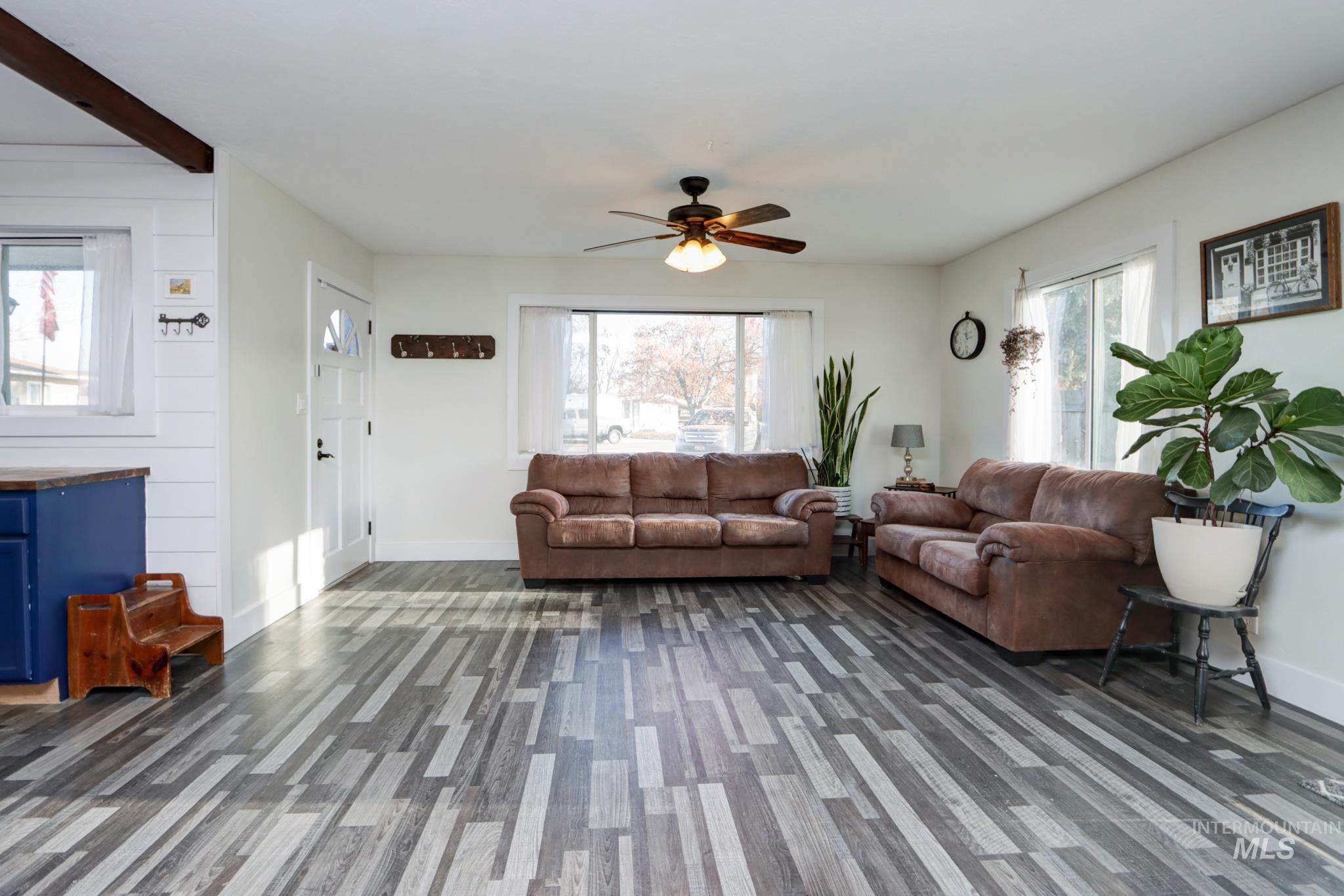 Living room featuring plenty of natural light, a ceiling fan, and beamed ceiling