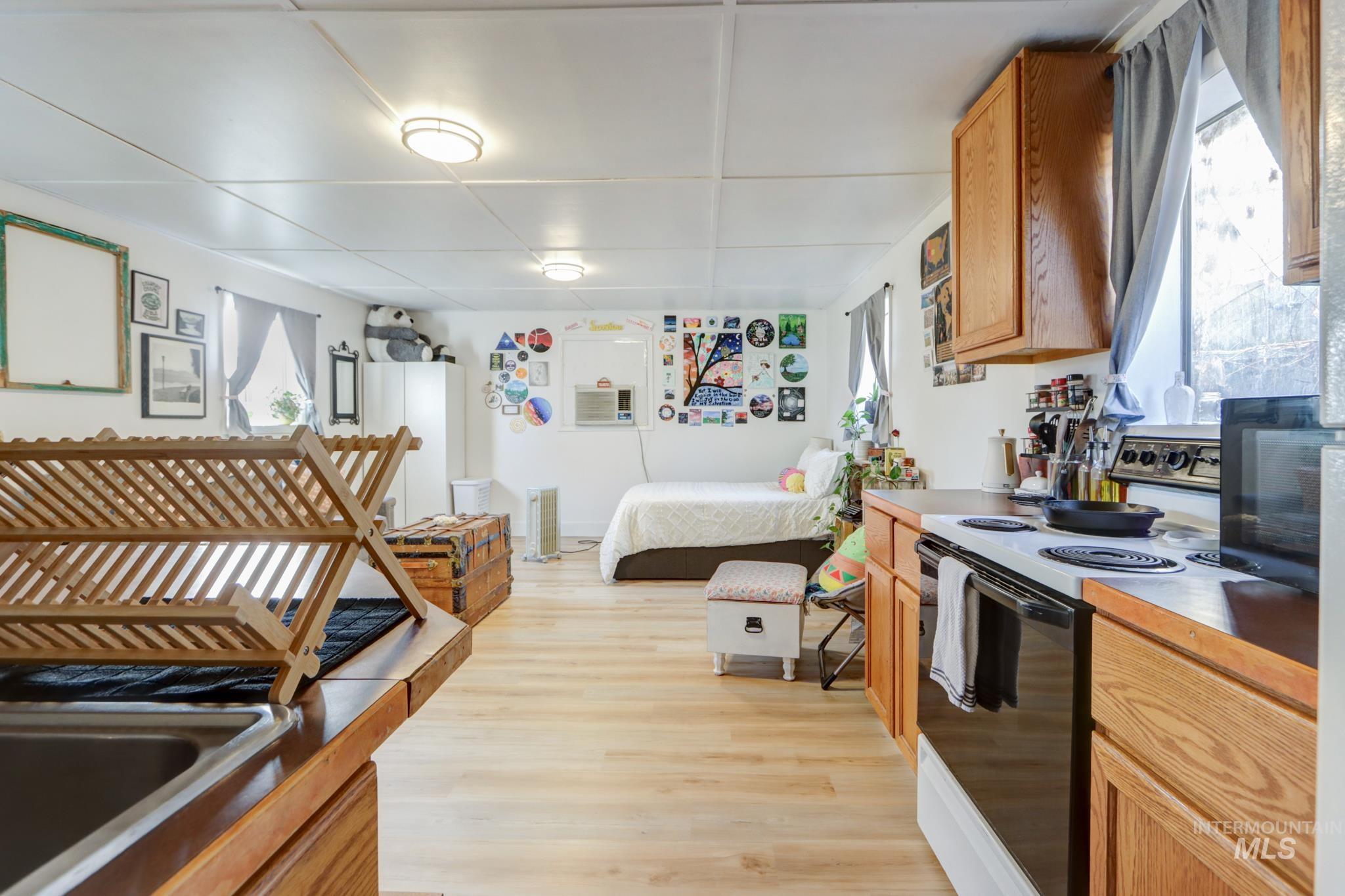 Kitchen featuring electric range oven, light wood-type flooring, black microwave, freestanding refrigerator, and open floor plan