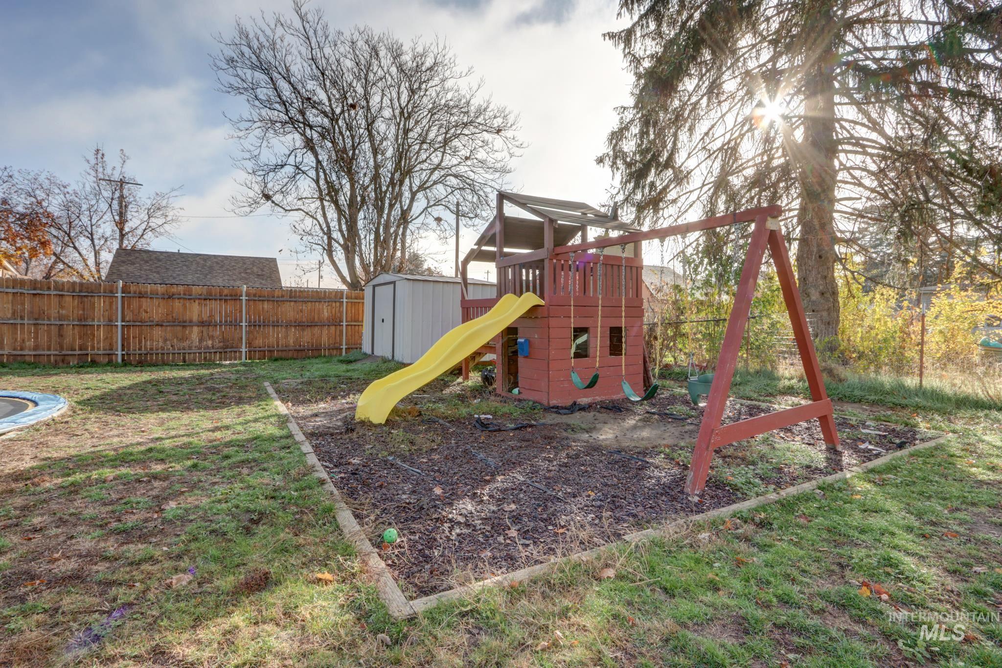 View of playground with a storage unit and a fenced backyard