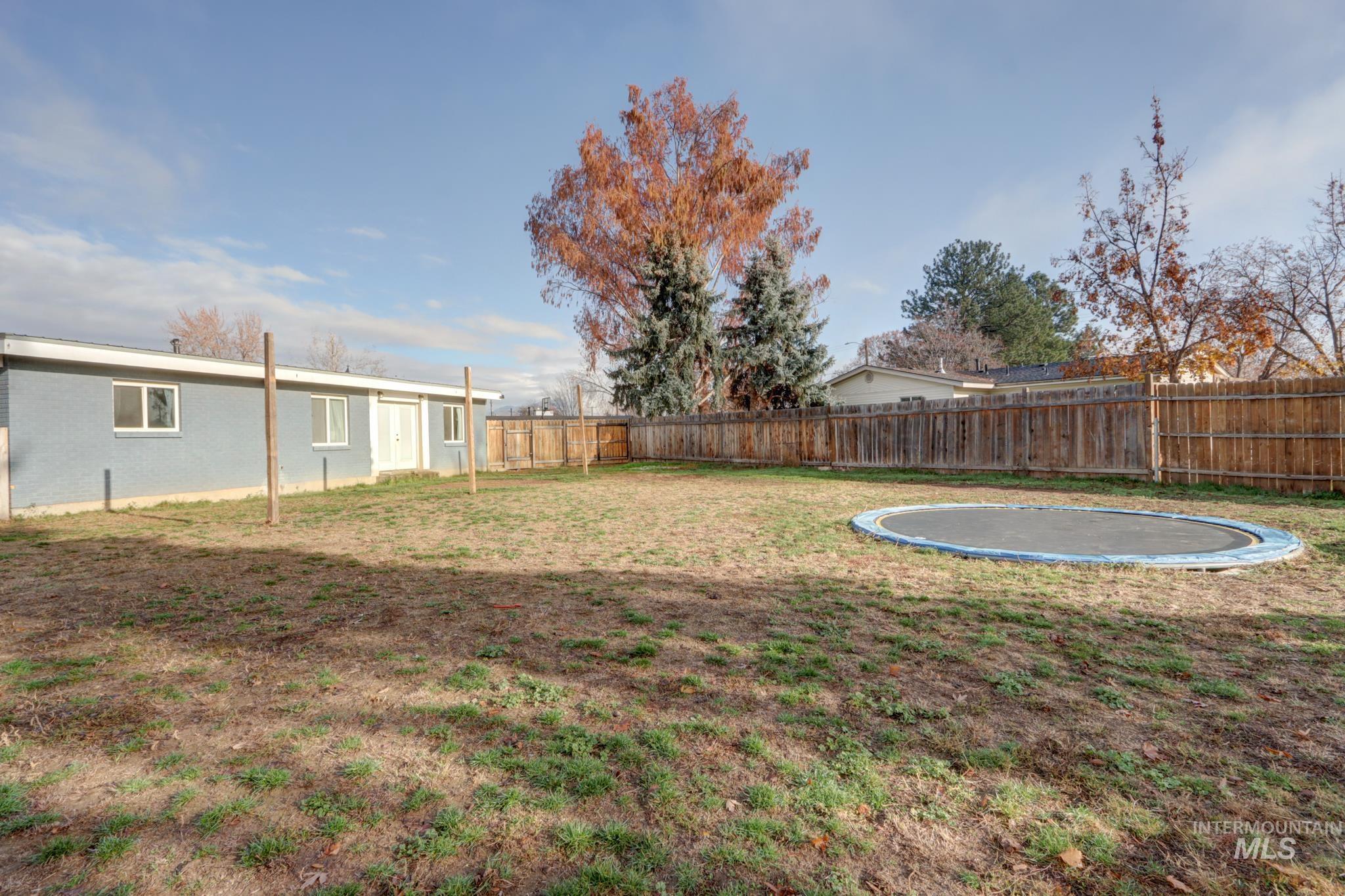 Fenced backyard featuring a trampoline