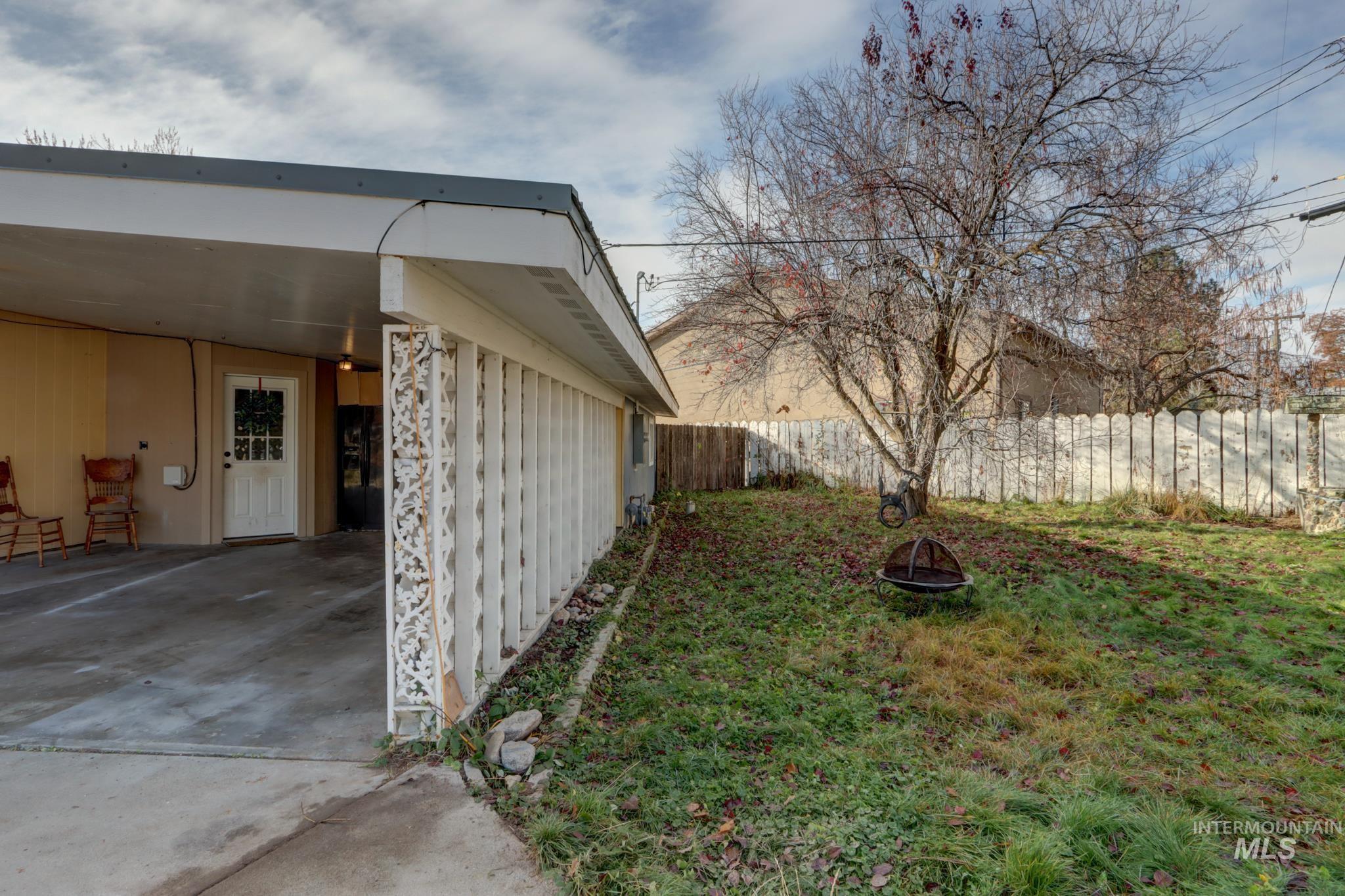 Fenced backyard with a carport, an outdoor fire pit, a patio area, and driveway