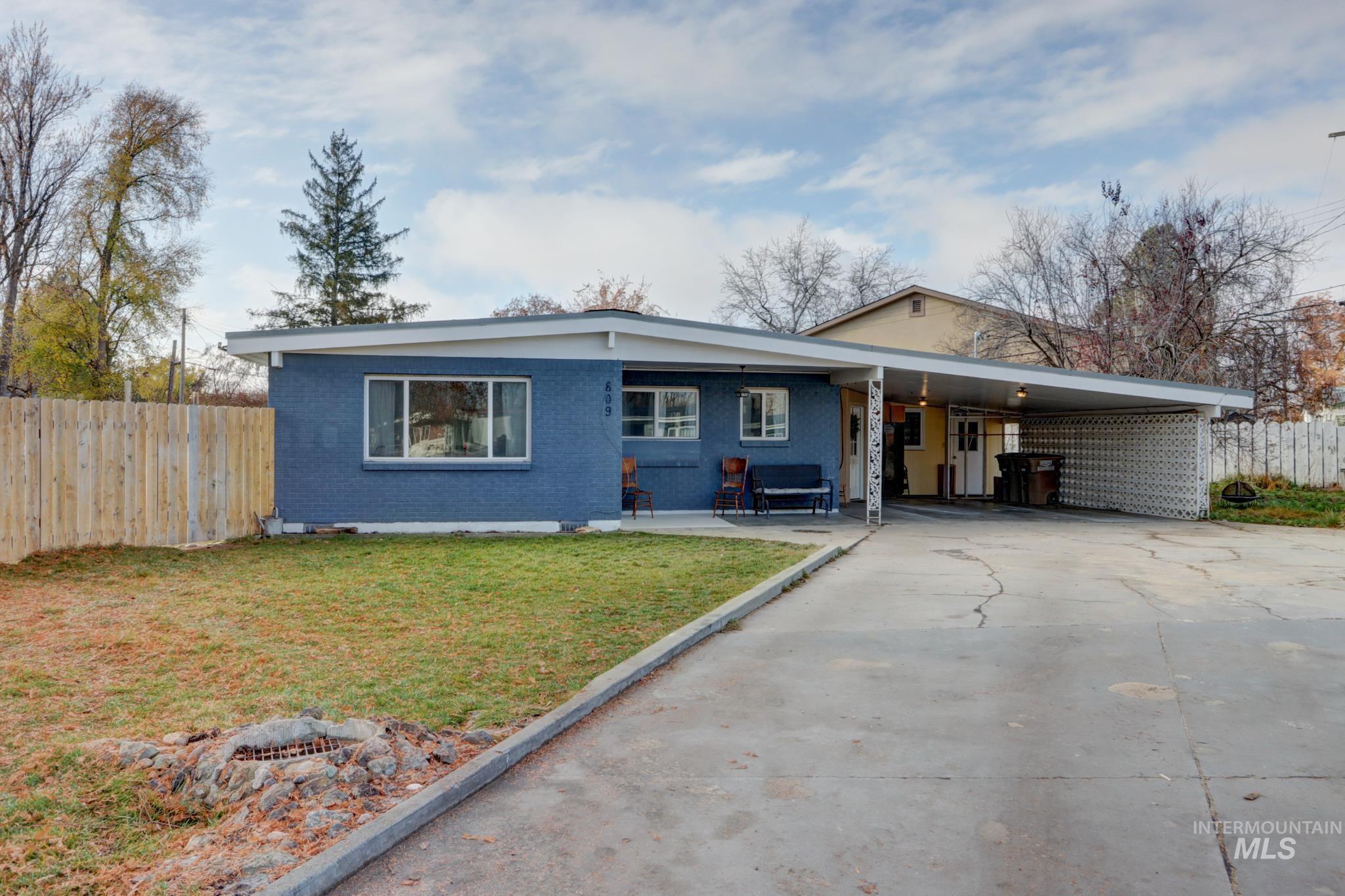 View of front of house featuring driveway, a carport, brick siding, and a patio area