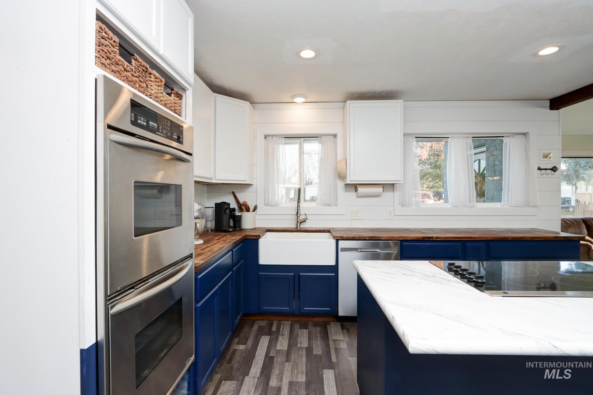 Kitchen featuring blue cabinetry, stainless steel appliances, wooden counters, recessed lighting, and dark wood finished floors