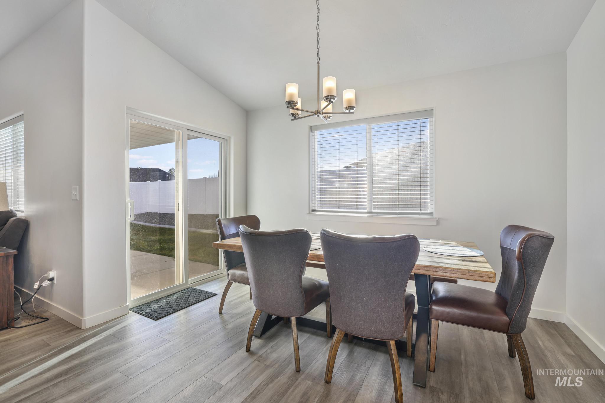Dining area featuring vaulted ceiling, wood finished floors, and a chandelier
