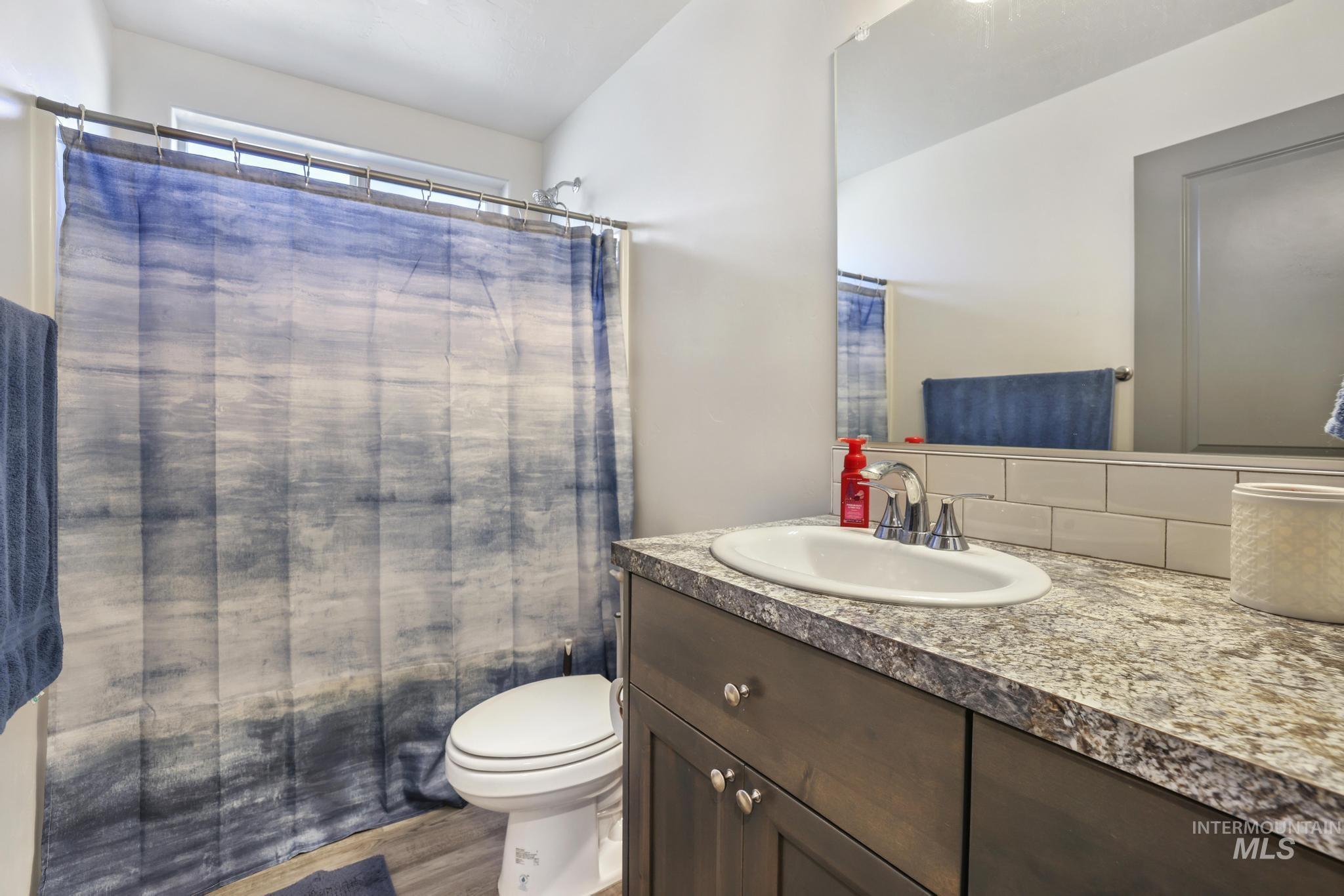 Bathroom featuring vanity, shower / tub combo with curtain, and wood finished floors