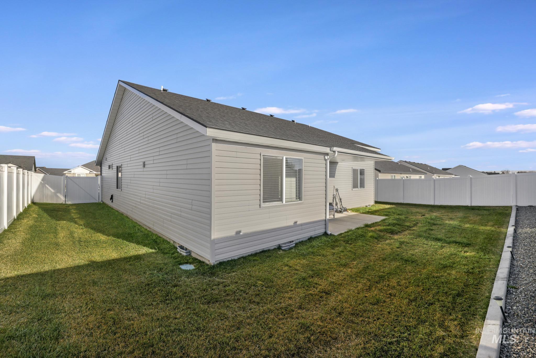 Back of property featuring a fenced backyard, a patio, and roof with shingles