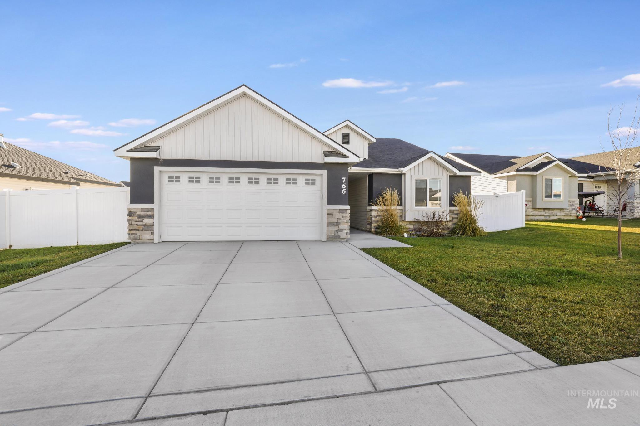 View of front facade featuring stone siding, driveway, board and batten siding, and an attached garage