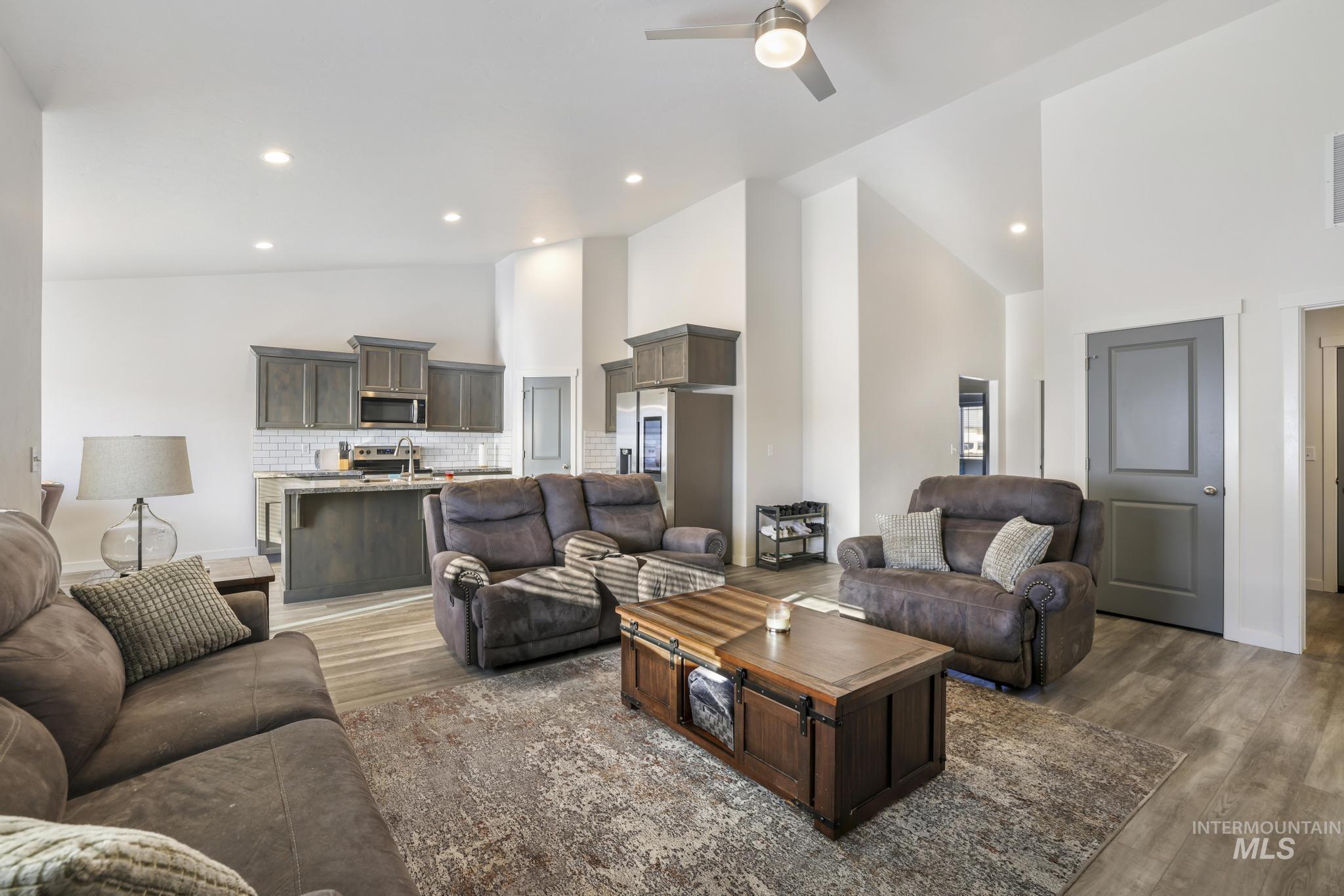 Living room featuring high vaulted ceiling, dark wood-style floors, a ceiling fan, and recessed lighting