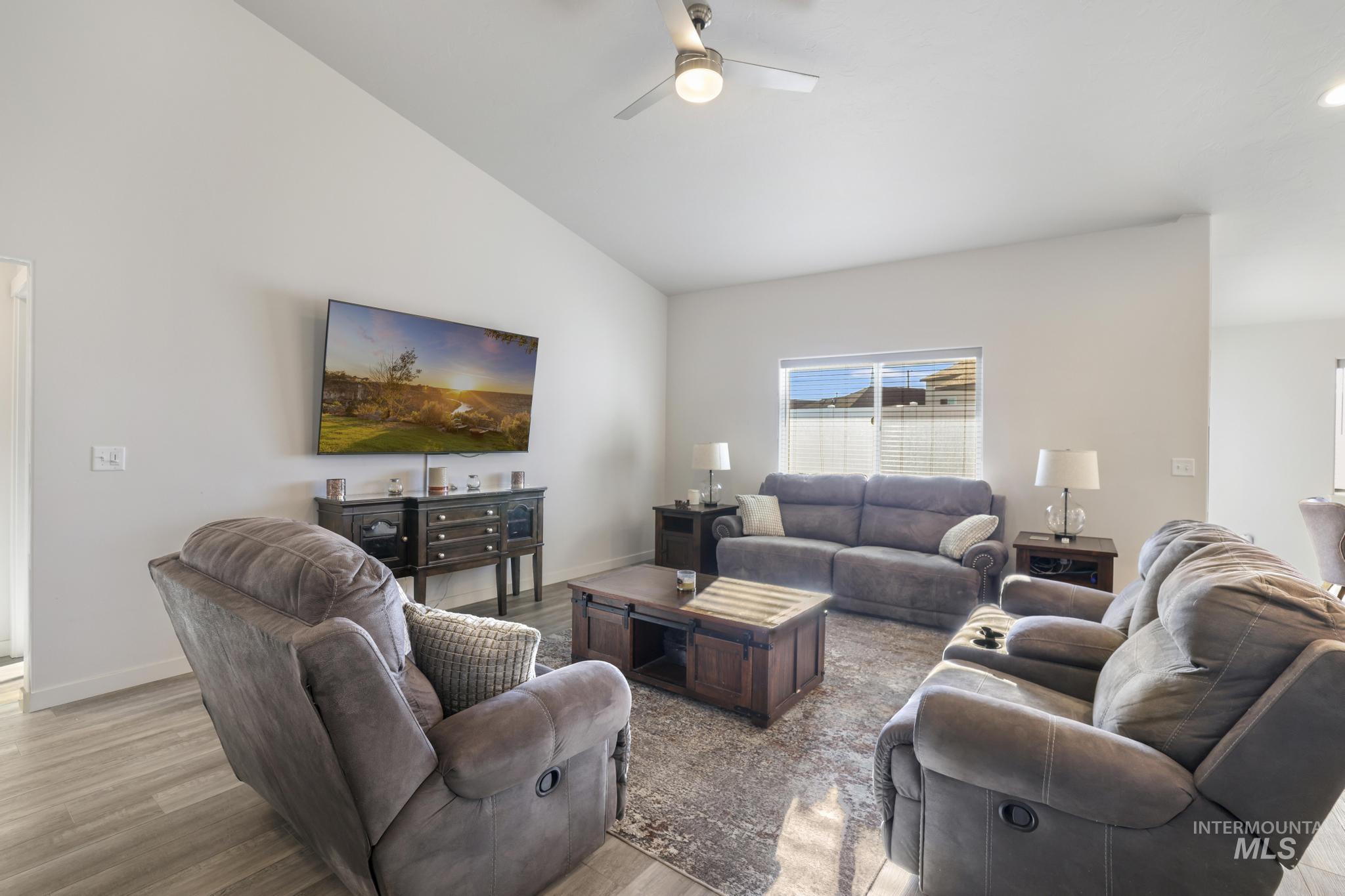 Living area with vaulted ceiling, wood finished floors, and ceiling fan