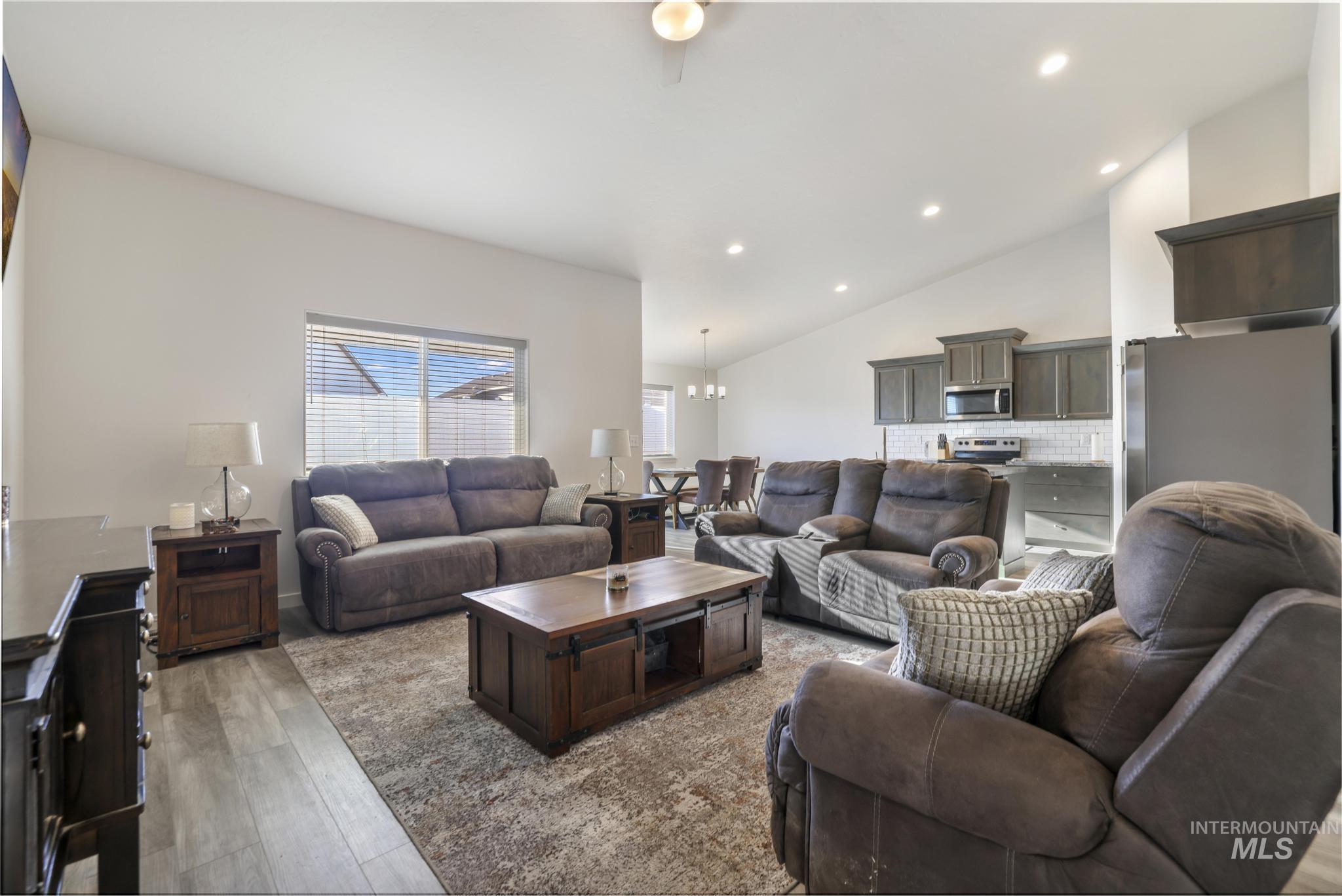 Living room with a chandelier, lofted ceiling, light wood-style floors, and recessed lighting