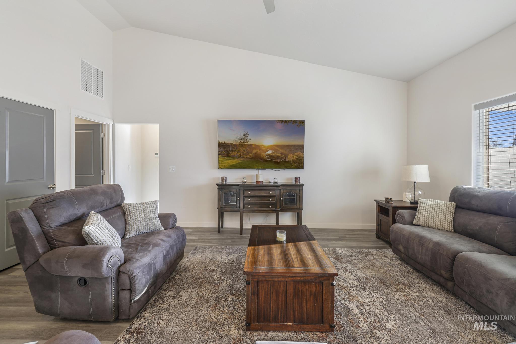 Living area with wood finished floors and high vaulted ceiling