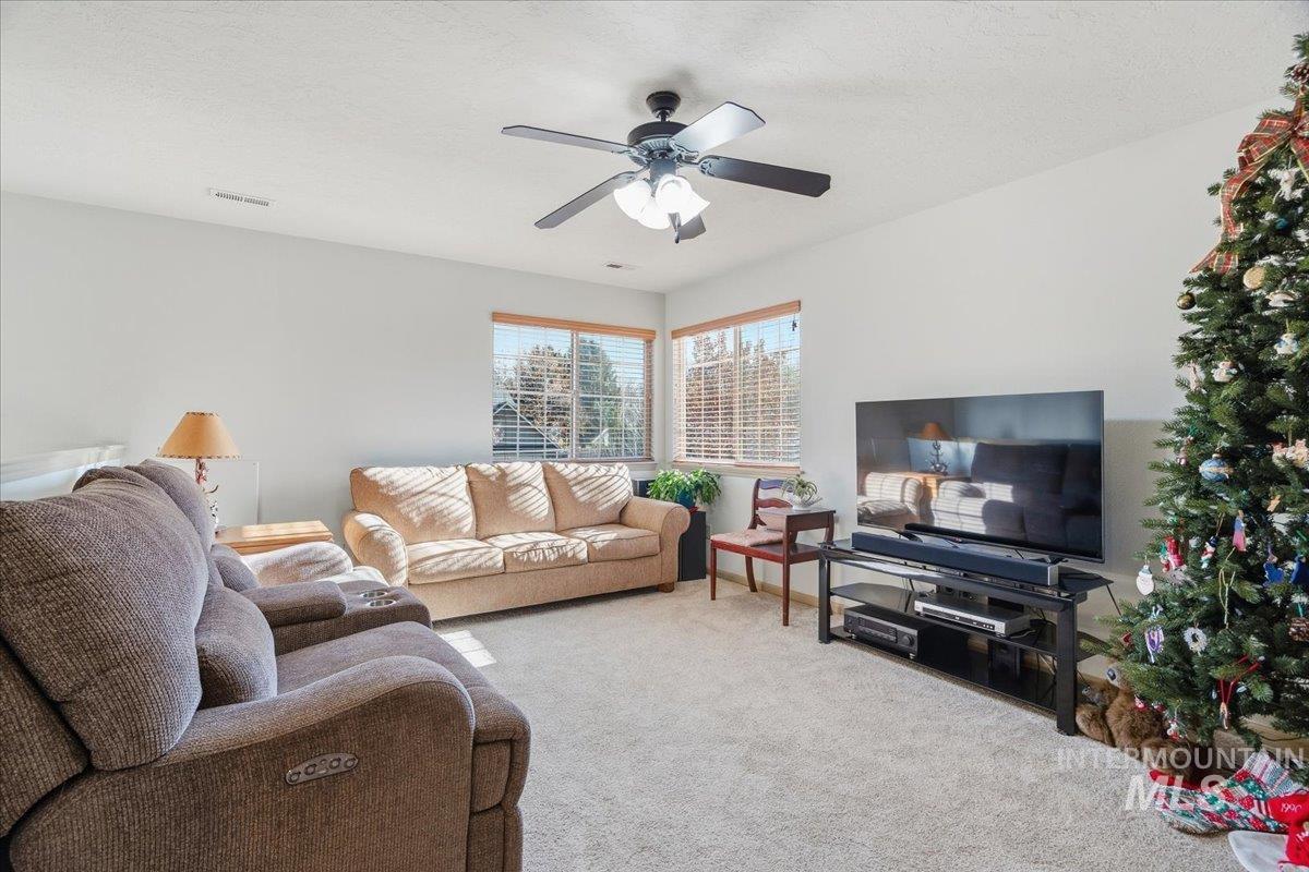 Carpeted living area featuring ceiling fan and a textured ceiling