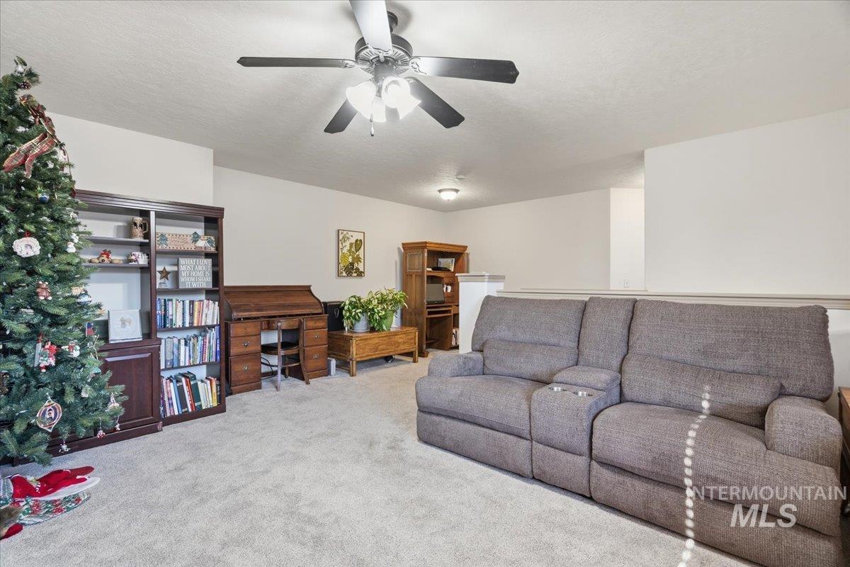 Living room featuring carpet, a textured ceiling, and ceiling fan