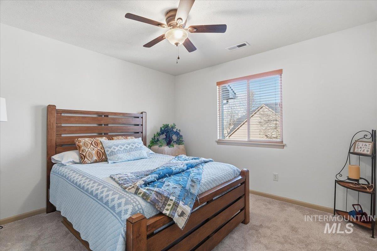 Bedroom with ceiling fan, light carpet, and a textured ceiling