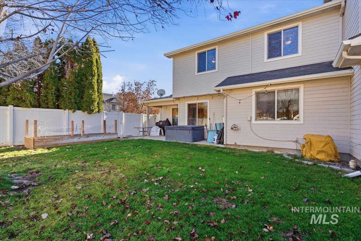 Rear view of house featuring a hot tub, a fenced backyard, and a patio area