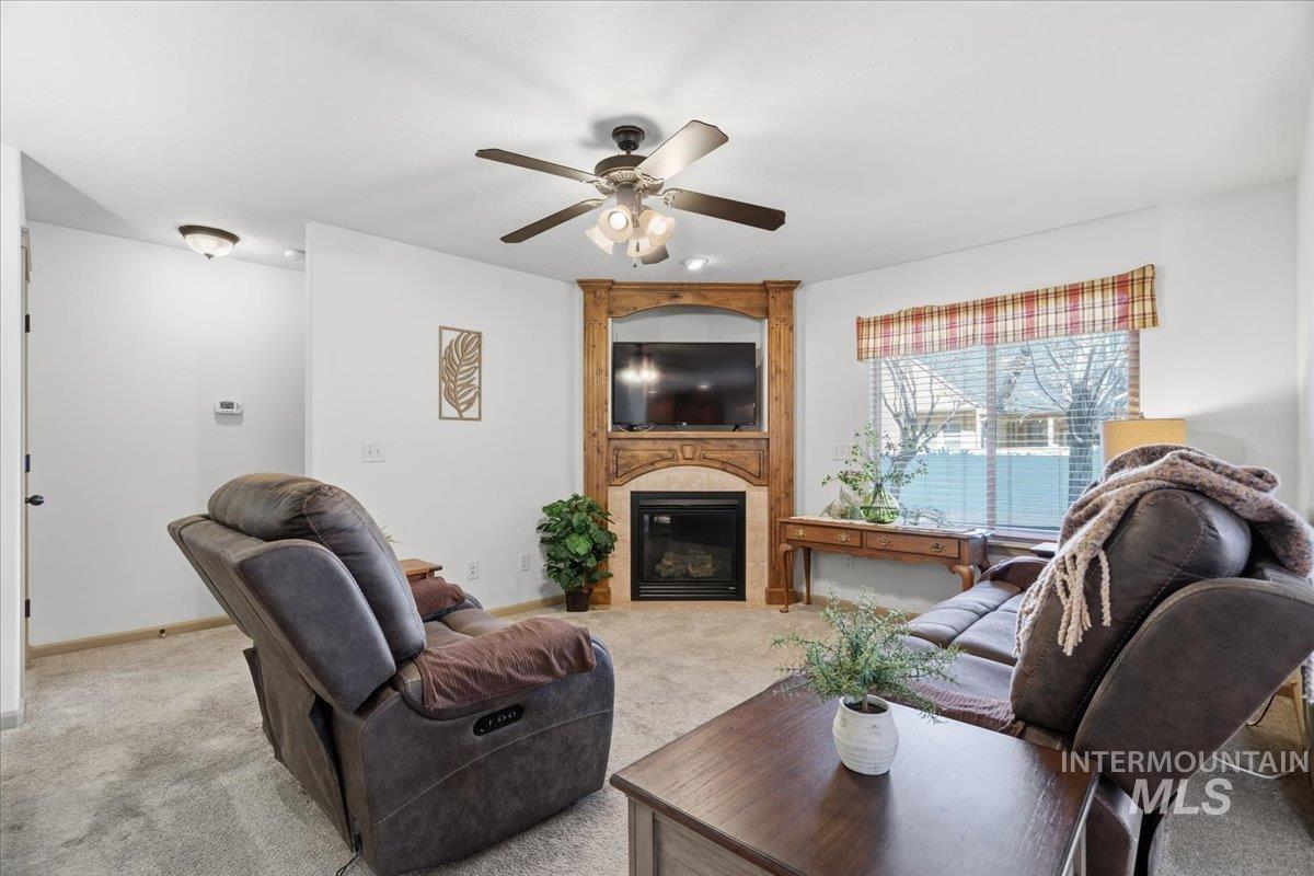 Carpeted living area with a fireplace and a ceiling fan