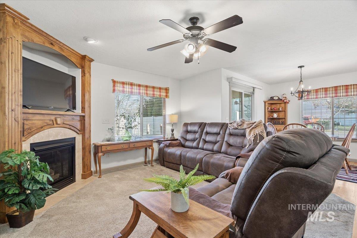 Living room with a chandelier, a large fireplace, carpet floors, and healthy amount of natural light