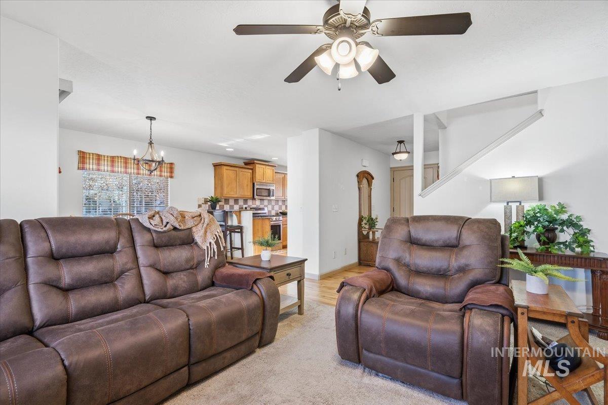 Living room with a chandelier, light wood-style flooring, a ceiling fan, and recessed lighting