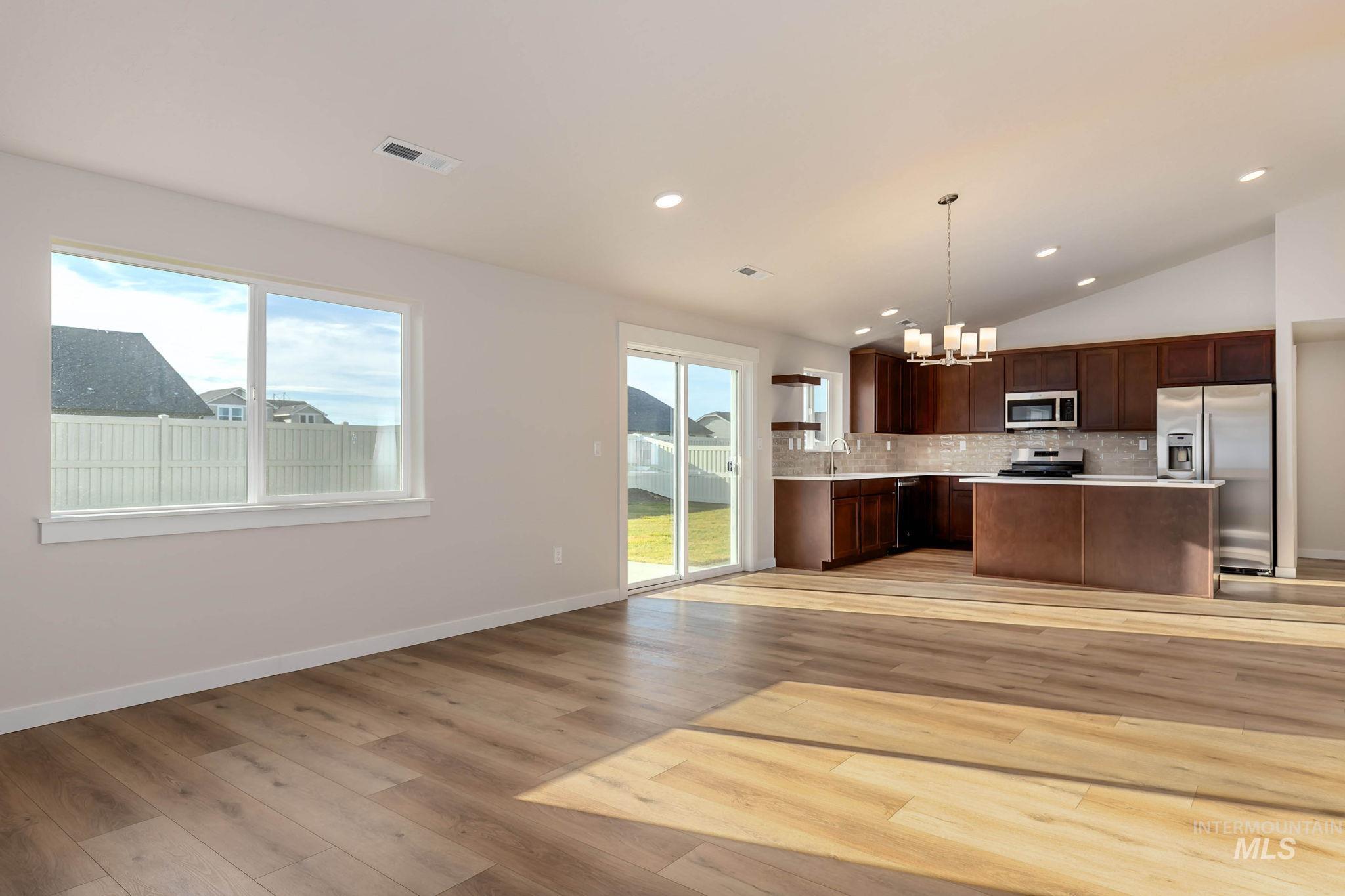 Kitchen with a kitchen island, vaulted ceiling, a chandelier, healthy amount of natural light, and light countertops