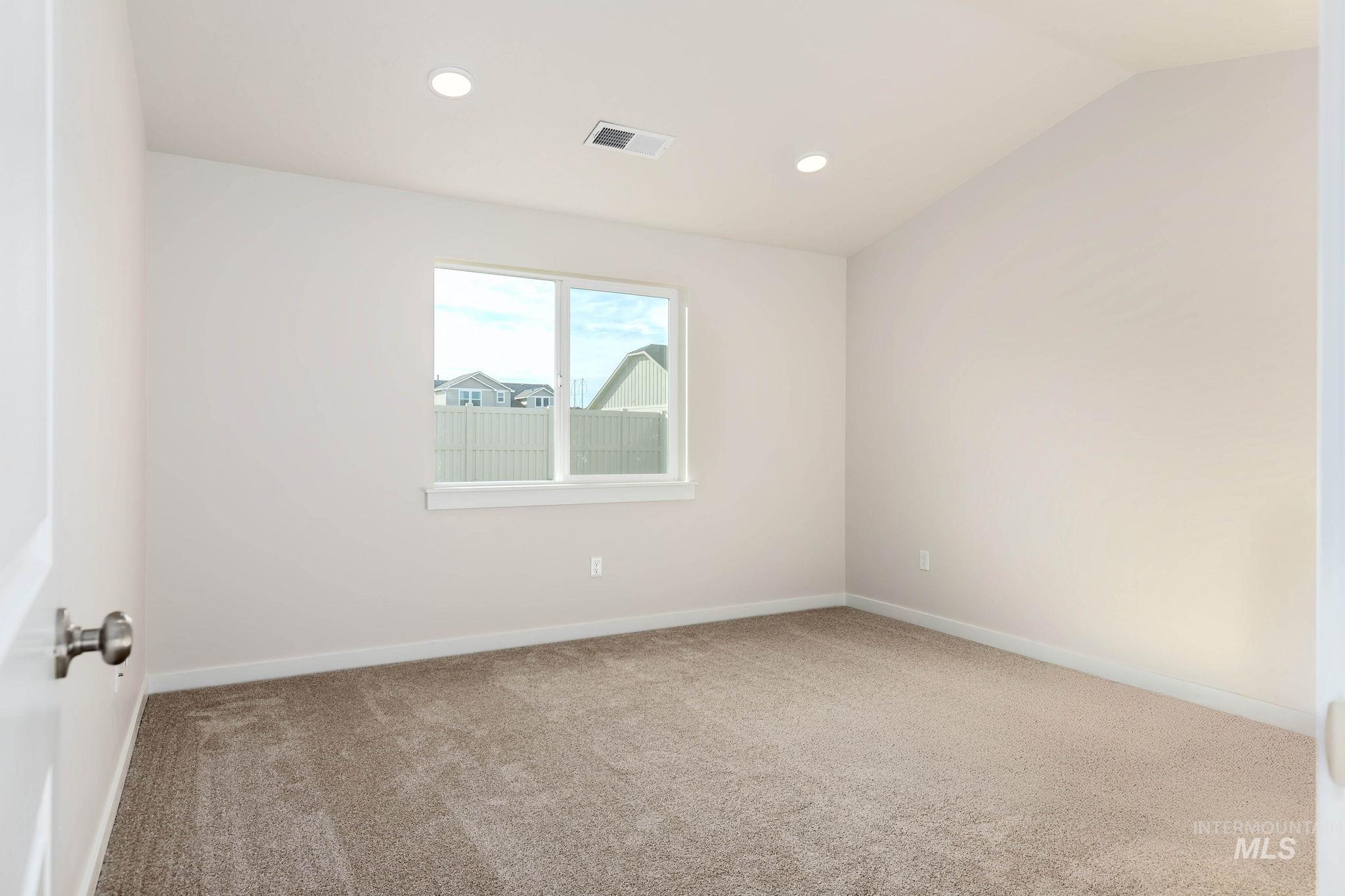 Carpeted empty room with recessed lighting and vaulted ceiling