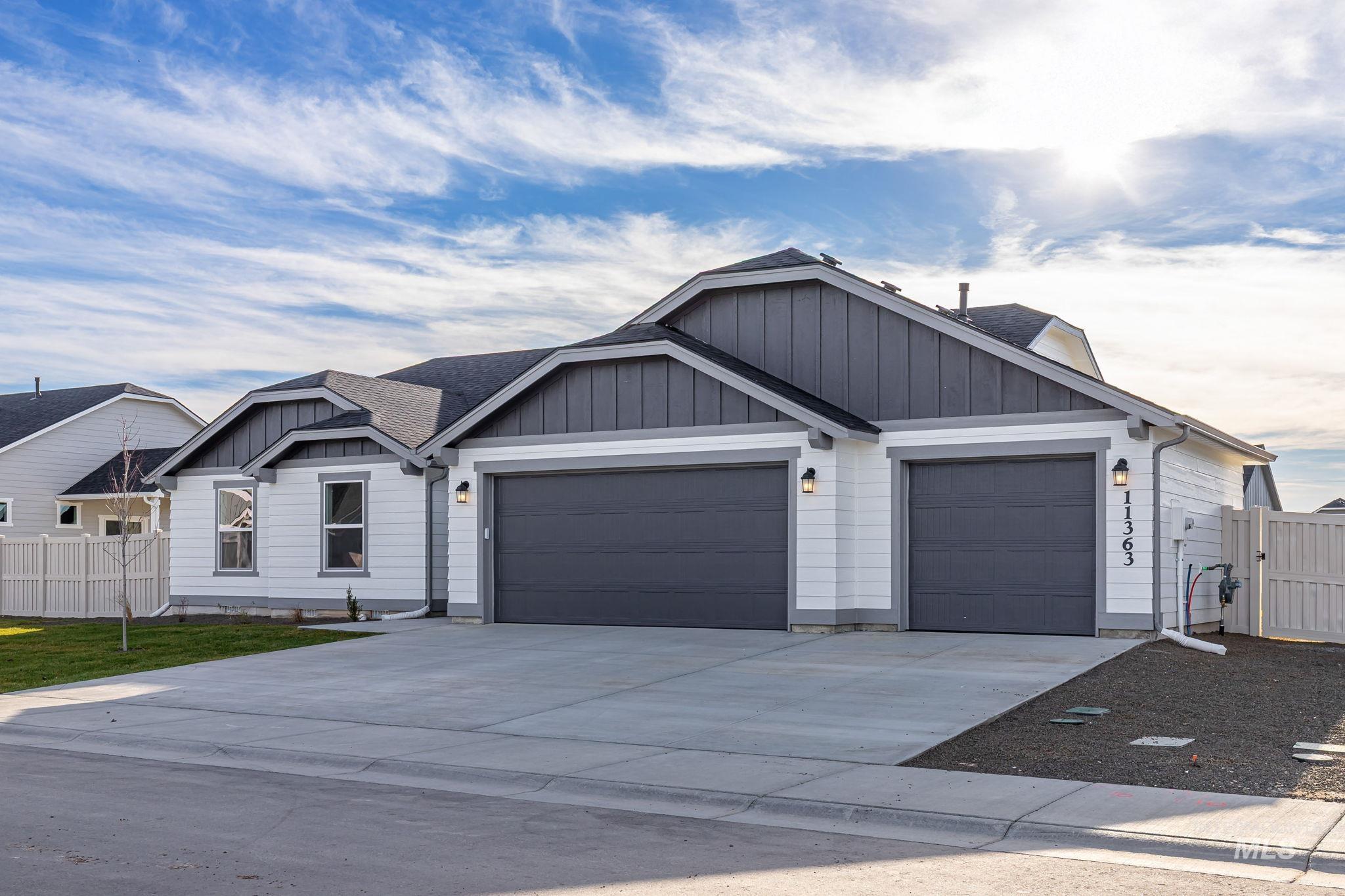 View of front of home featuring board and batten siding, driveway, an attached garage, and roof with shingles