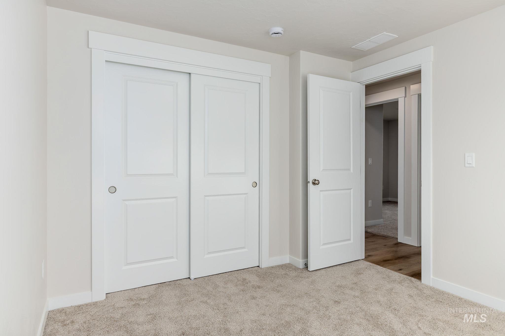 Unfurnished bedroom with light carpet and a closet